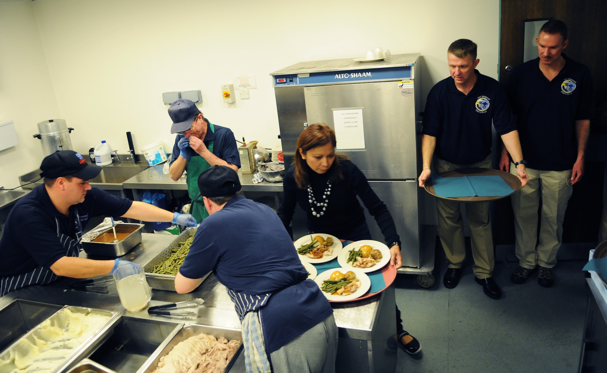RAF MIILDENHALL, England -- Chief Master Sgt. Somjai Hensley, 100th Mission Support Group, takes a tray of food to a portion of the 350 participants of the Special Persons' Holiday Party at the Galaxy Club here Dec. 11, 2010. Volunteers from around base gathered the names, ages and Christmas wishes of guests to personalize their experience. (U.S. Air Force photo/Staff Sgt. Thomas Trower)