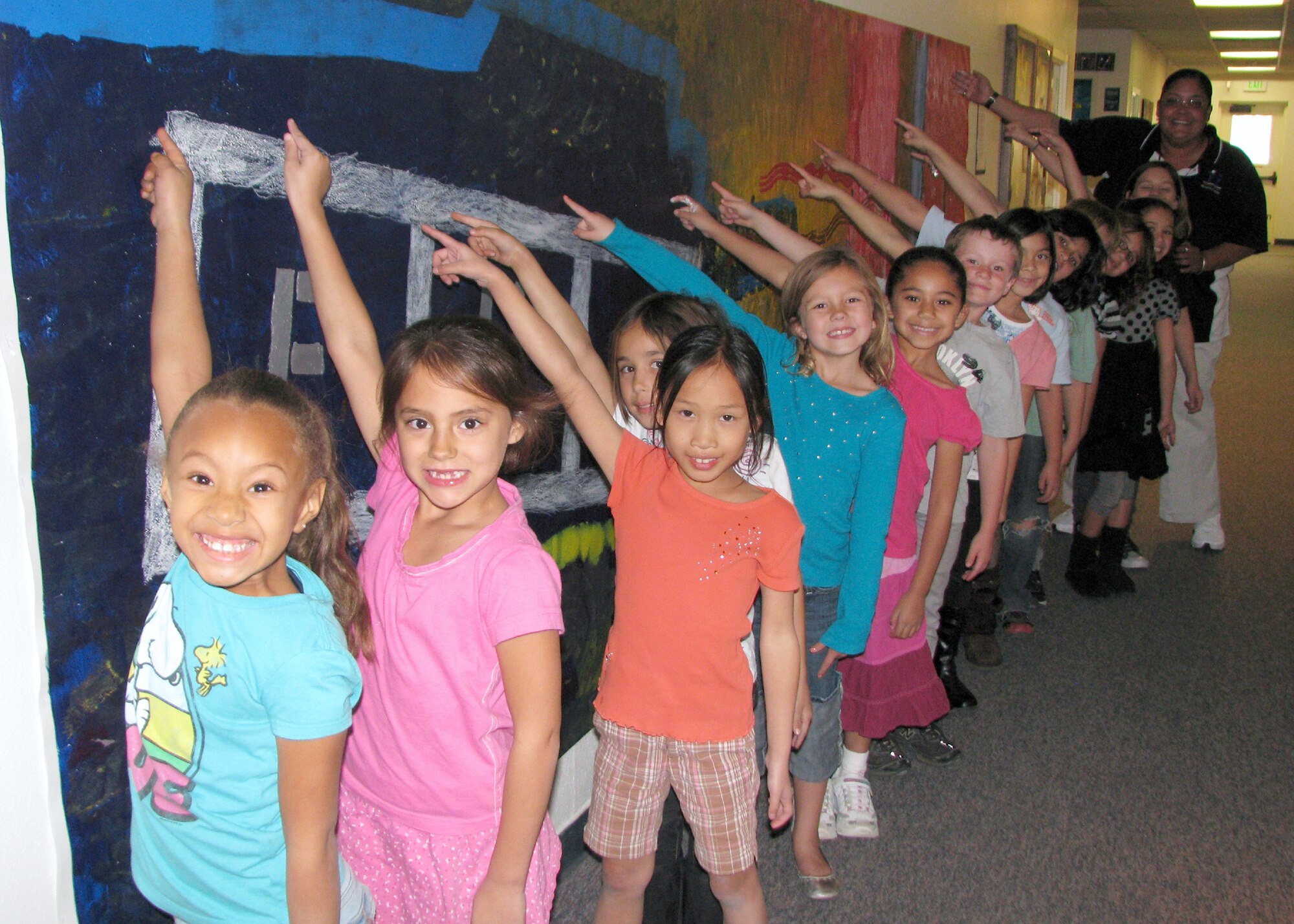 Jacinta Cross' afternoon arts and crafts class students proudly stand by the 10-foot-long mural they created together. (Air Force photo by Diane Betzler)