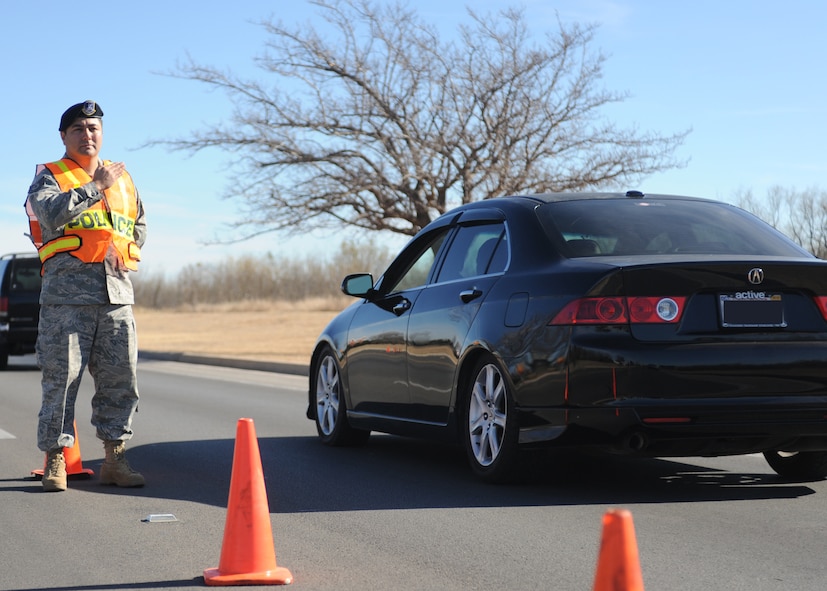 DYESS AIR FORCE BASE, Texas -- Tech. Sgt. Ricardo Flores, 7th Security Forces Squadron, directs traffic to one lane to screen for individuals not wearing seatbelts and illegally using cellular phones Dec. 14, here.  Using a cellular phone while driving increases the chances of getting into an accident by 400 percent and failure to wear a seat belt contributes to more fatalities than any other single traffic safety-related behavior. (U.S. Air Force photo/Senior Airman Jenifer H. Calhoun)
