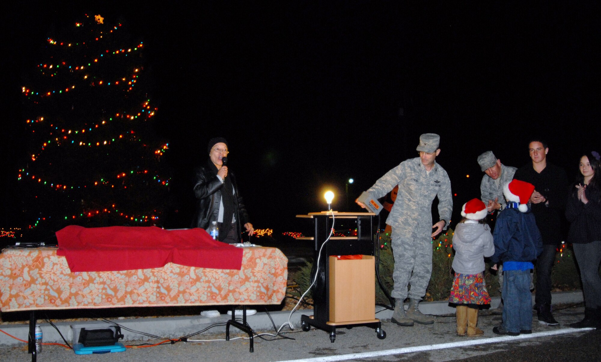Col. Gregory E. Schwab, 95th Air Base Wing commander, along with children of deployed service members, lights up the annual holiday tree in front of the Base Exchange, Dec. 7. (Air Force photo by Kenji Thuloweit)
