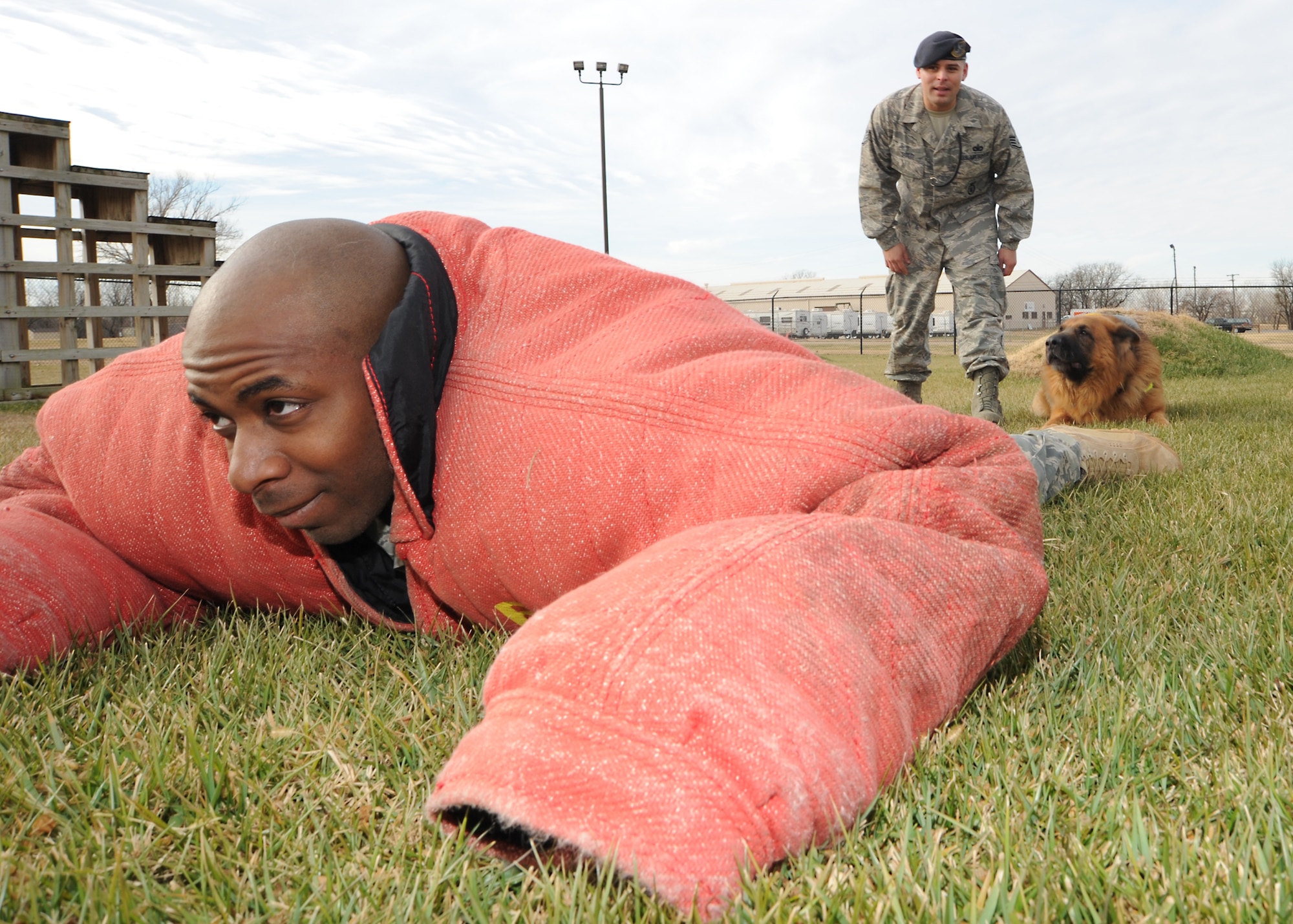 Staff Sgt. Travis Dulworth, 22nd Security Forces Squadron military working dog handler, lays on the ground while Staff Sgt. Max Soto, 22nd Security Forces Squadron military working dog kennel master, gives challenge commands alongside his K-9, “Atom,” during controlled aggression training Dec. 9, 2010, McConnell Air Force Base, Kan. In controlled aggression training, the dog handler utilizes the K-9, with and without commands, to seek, detect, bite or hold a suspect for effective control. During threatening situations, the K-9 can protect and deter attacks on their handler. (U.S. Air Force photo/Senior Airman Maria A. Ruiz)  