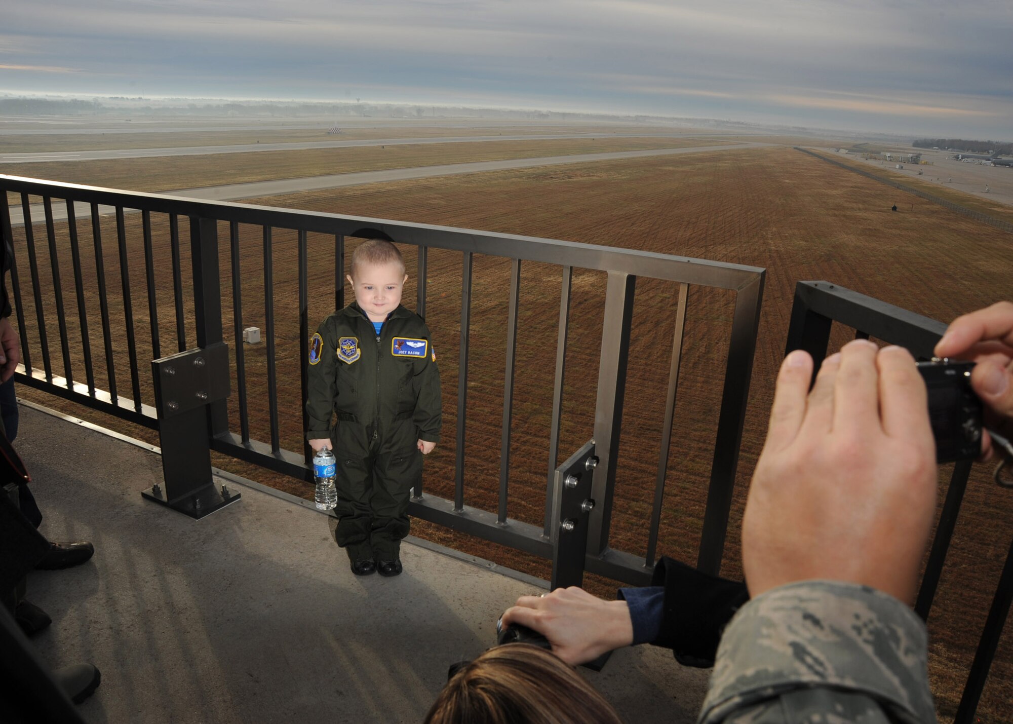 Five-year-old Joey Bacon, Pilot For a Day recipient, poses for photographs at the air traffic control tower catwalk Dec. 10, 2010, McConnell Air Force Base, Kan. Joey, who was diagnosed with leukemia, was invited to the base by members of the 22nd Operations Support Squadron as part of the Pilot For a Day program, an Air Force program that allows medically-challenged youth a chance to visit a base and become part of the Air Force team. (U.S. Air Force photo/Staff Sgt. Dallas Edwards)