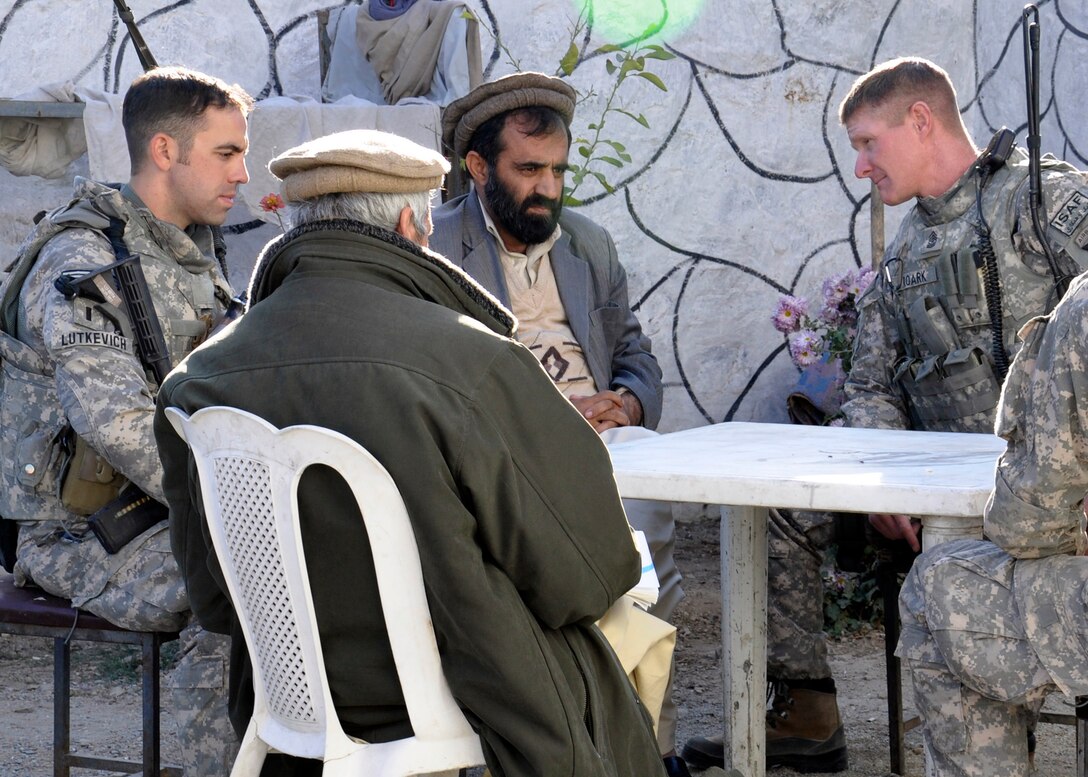 U.S. Army Sgt. Maj. Jason Roark, right, talks to the leader of the prison system in Nuristan, Mohammed Masom, as U.S. Army 1st Lt. Michael Lutkevich, platoon leader for the Provincial Reconstruction Team security force, listens in Nuristan Province, Afghanistan, Nov. 24, 2010. The Nuristan Provincial Reconstruction Team works with leaders like Masom to help them sustain operations through reaching back to their own government. 