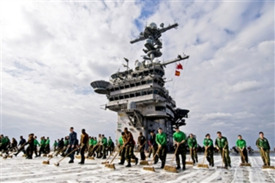 U.S. Navy sailors assigned to the aircraft carrier USS George Washington and embarked Carrier Air Wing 5 scrub the flight deck in the Pacific Ocean on Dec. 13, 2010.  The George Washington will undergo interior and exterior preservation, renovations and repairs upon return to its permanently forward-deployed port at Commander, Fleet Activities Yokosuka, Japan.  