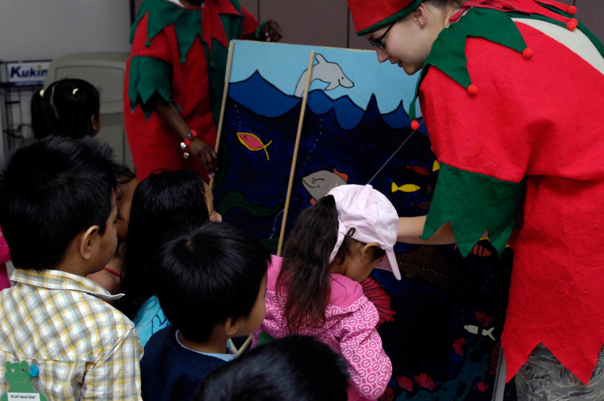 A military volunteer (right) assists children with "fishing"  at the Oahu Head Start Program Holiday Party at the Makai Recreation Center at Joint Base Pearl Harbor-Hickam, Hawaii Dec. 16. A visit from Santa Claus, a magic show, and other activities highlighted the volunteer effort by base members to brighten the holiday spirit formore than 100 underpriviledged children. (U.S. Navy photo by David D. Underwood, Jr.)