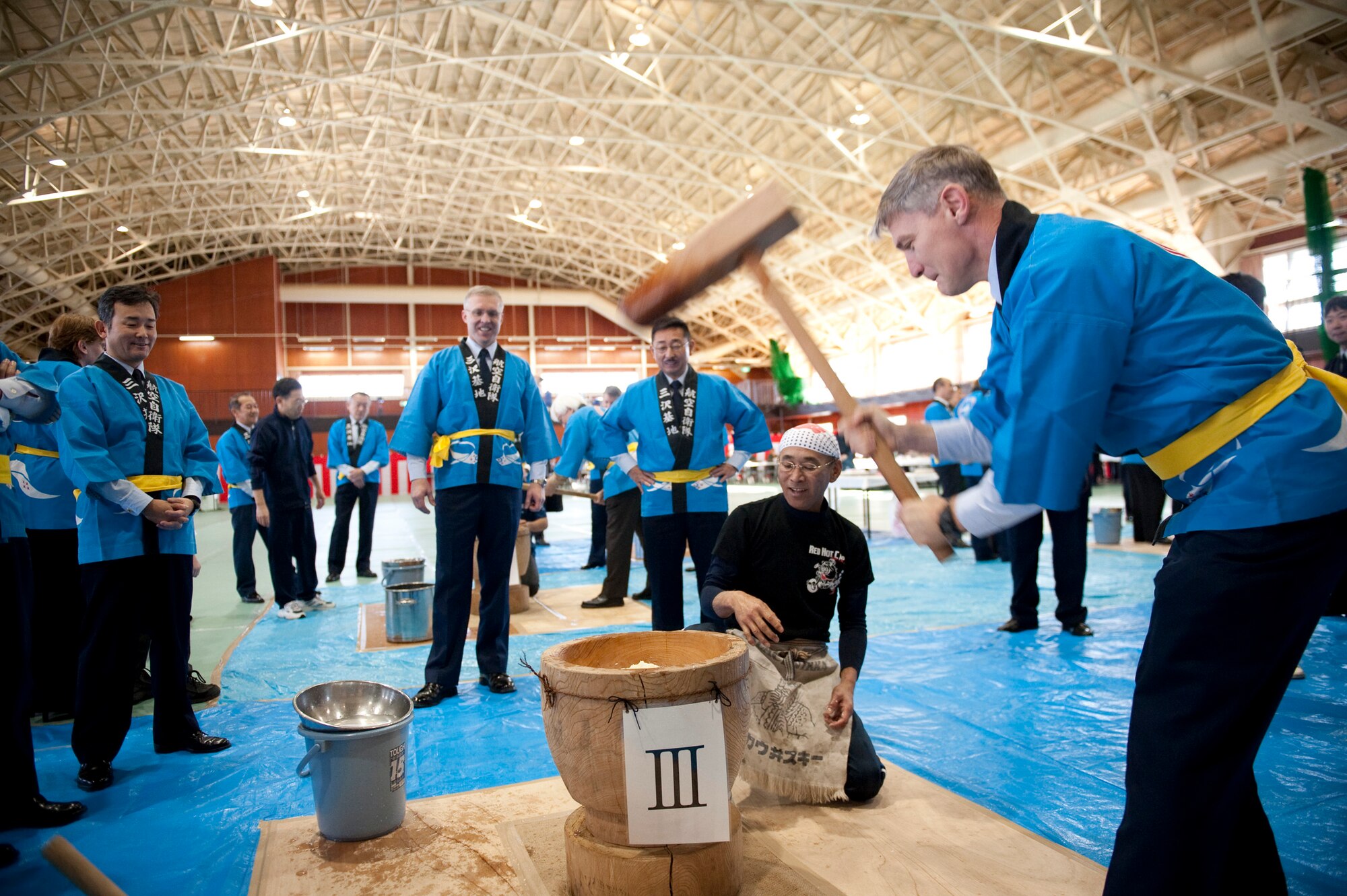 U.S. Air Force Col. John Pearse, 35th Operations Group commander, pounds mochi during the annual mochi pounding ceremony at the Japan Air Self-Defense Force gym, Misawa Air Base, Japan; Dec. 16, 2010. Mochi is a type of rice cake made by pounding steamed, glutinous rice in a large wooden mortar with a large wooden mallet. (U.S. Air Force photo by Staff Sgt. Samuel Morse/Released)