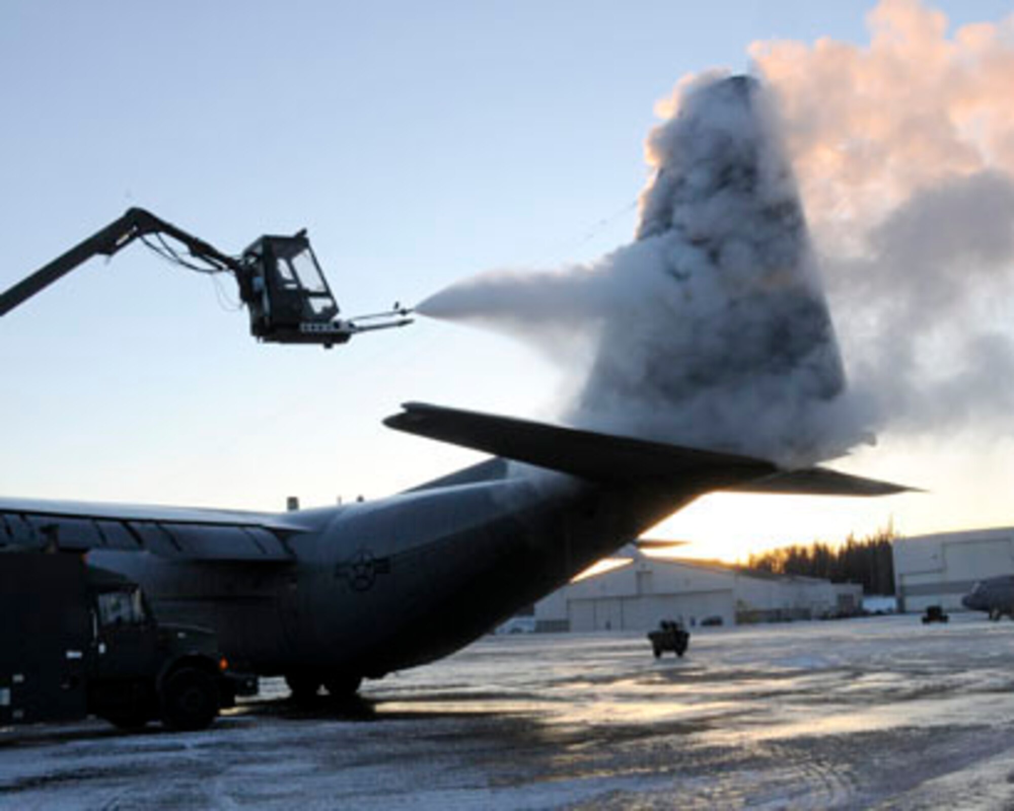 KULIS AIR NATIONAL GUARD BASE, Alaska - Senior Airman Michael A. Gushue, a crew chief with the 176th Aircraft Maintenance Squadron, de-ices a C-130 "Hercules" tactical airlift aircraft as Staff Sgt. Roy Eason from the 176th Aircraft Maintenance Squadron, drives the de-ice truck here Dec. 16, 2010. Alaska Air National Guard photo by Staff Sgt. N. Alicia Goldberger.