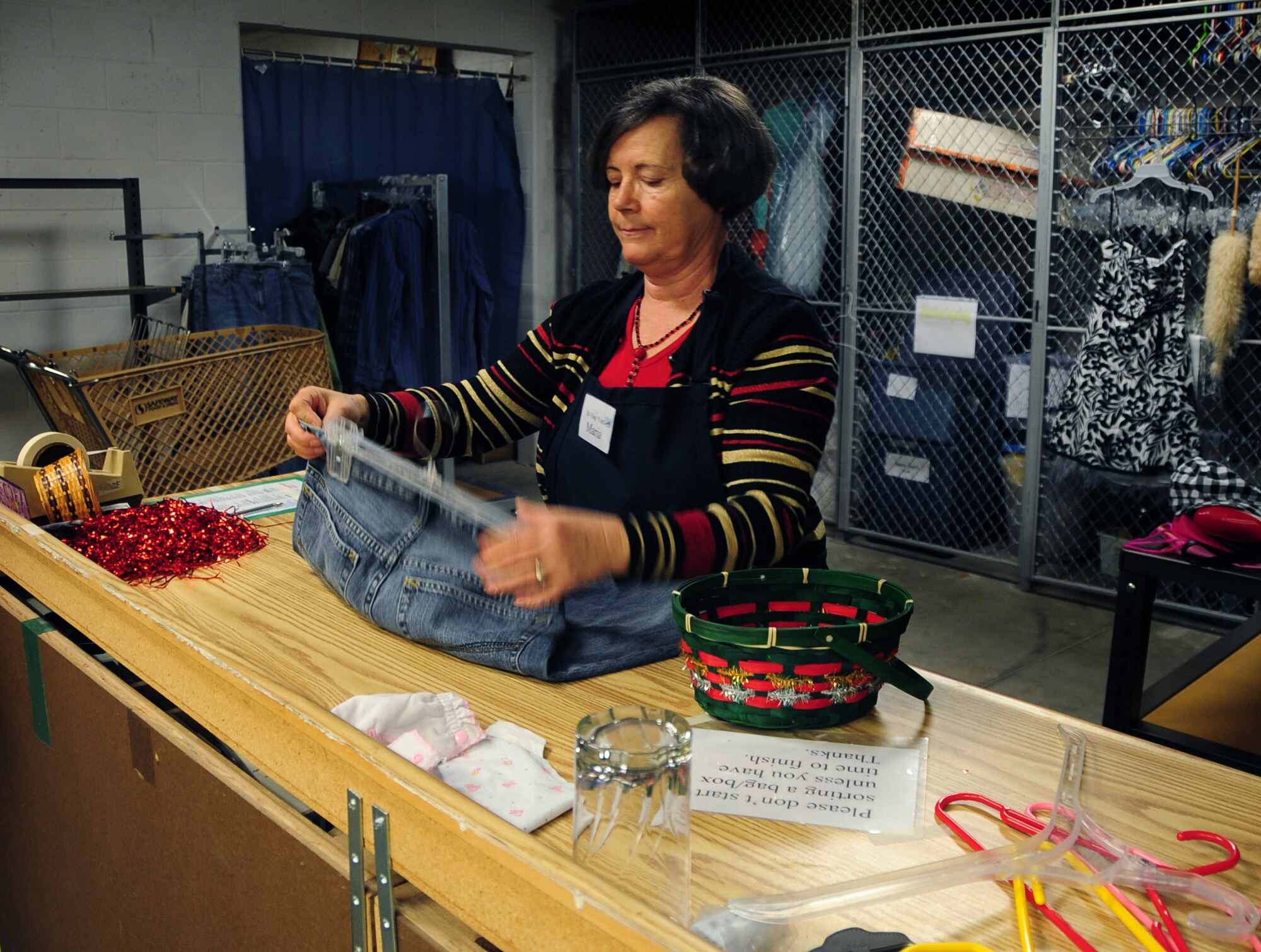 ELLSWORTH AIR FORCE BASE, S.D. -- Maria Gavle, a volunteer working at the B-One Yard Thrift store, attaches hangers and price tags to clothes, Dec. 16.  The thrift store provides a place for Airmen and their families to purchase items donated by other Airmen at reasonable prices. (U.S. Air Force photo/Senior Airman Anthony Sanchelli)
