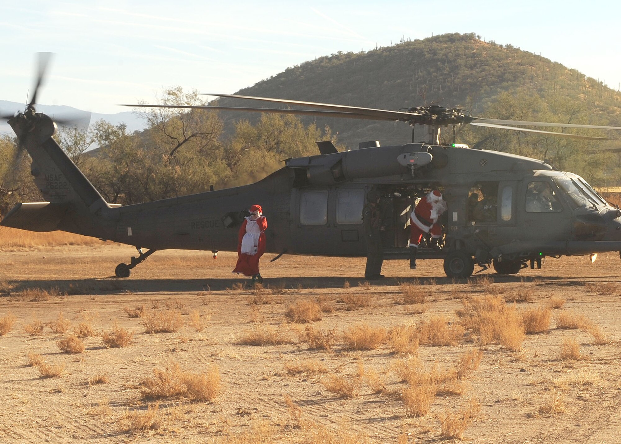 Master Sgt Cesar Medina, Santa, from the 612 Air Operation Center, and Staff Sgt Jennifer Fore, Ms. Clause, also from the 612th Air Operation Center, land in an HH-60 at the San Xavier Mission School in participation of Santa?s in Blue, December 9, 2010. Davis-Monthan has travel to several schools to give kids from low income families gifts for Christmas since 1965. (U.S. Air Force photo/Senior Airman Brittany Dowdle) (RELEASED)