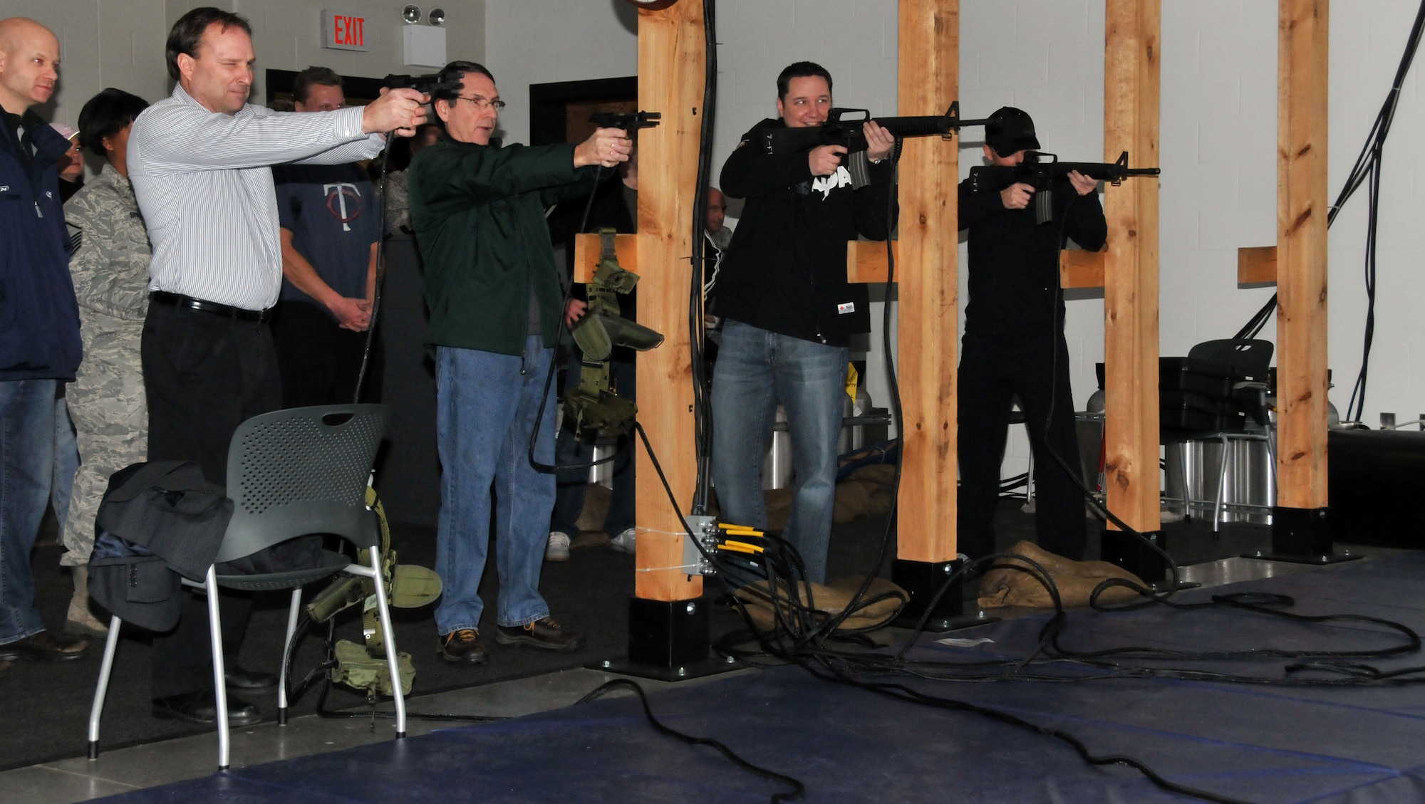 Members of the Minnesota Wild, Defending the Blue Line and National Hockey League Players Association take a few shots with the Firearms Training Simulator during their tour of the 934th Security Forces Squadron Dec. 16. (Air Force Photo/Paul Zadach)