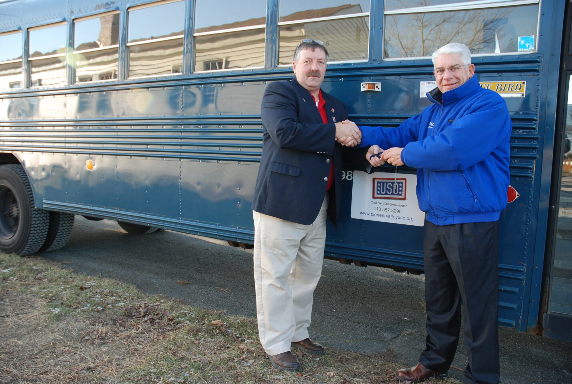 Al Tracy, president of the Pioneer Valley USO at Westover, takes the keys of a newly-donated bus from James Carey, Phoenix Management Inc. project manager, Dec. 16. Phoenix and the USO work together frequently to assist deploying Airmen of the 439th Airlift Wing. (US Air Force photo/Master Sgt. Andrew Biscoe)