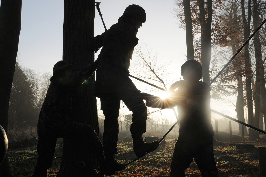 Airmen from Royal Air Force Mildenhall, England, and RAF Marham, England, help a teammate cross a set of ropes at the low-ropes course during a joint training day Dec. 6, 2010, at RAF Marham. This activity required leadership and mental and physical strength of participants to get all team members to the finishing point. (U.S. Air Force photo/Senior Airman Tabitha M. Lee)
