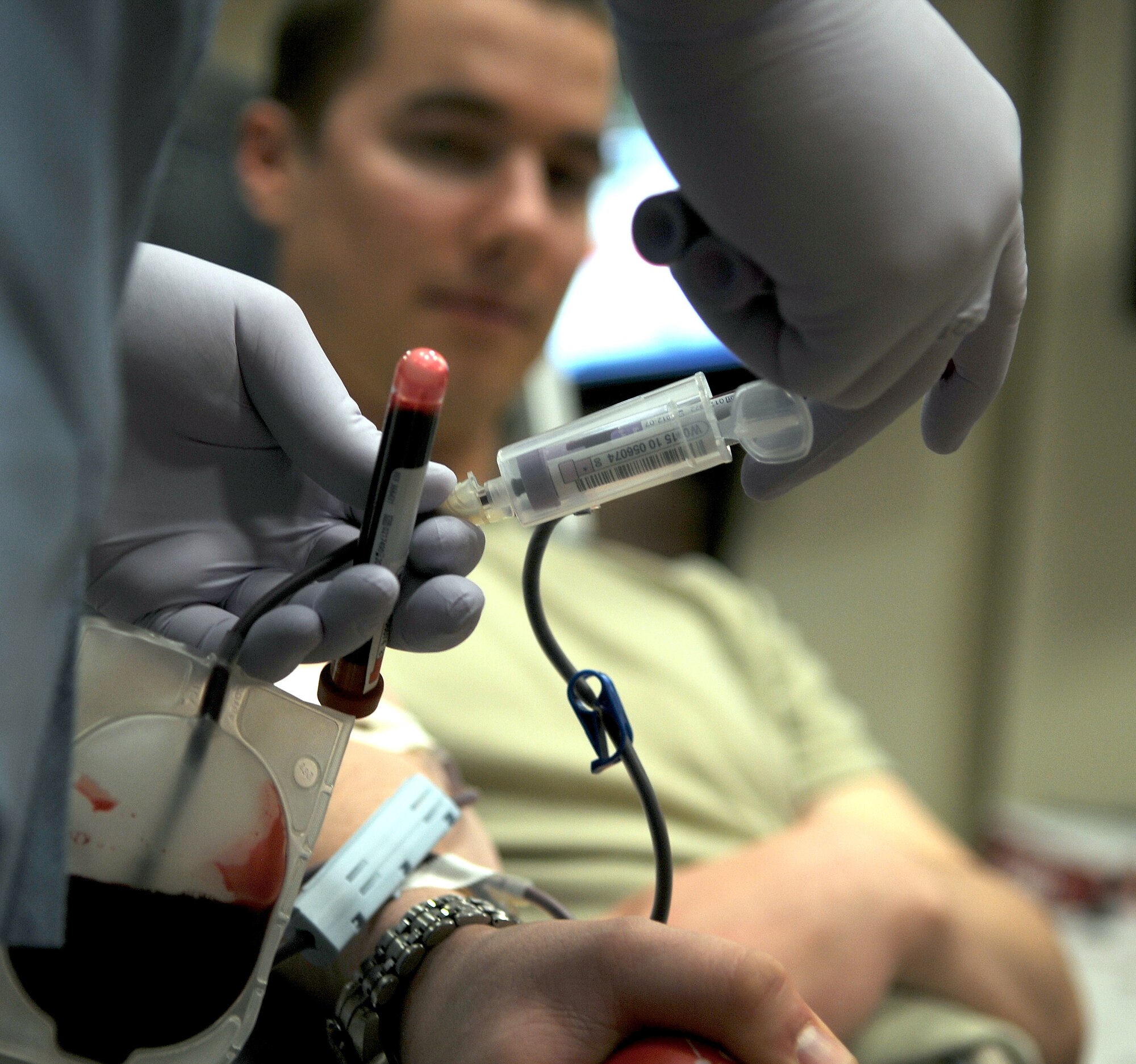 GOODFELLOW AIR FORCE BASE, Texas – Airman 1st Class Matthew West, 316th Training Squadron student, watches as samples of his blood are collected in test tubes during a blood drive at the Events Center here Dec 15. Airman West is one of many who volunteered to donate a pint of blood to The United Blood Services. All donated blood is tested for blood borne pathogens in order to protect transfusion patients. (U.S. Air Force photo/Staff Sgt. Heather L. Rodgers)