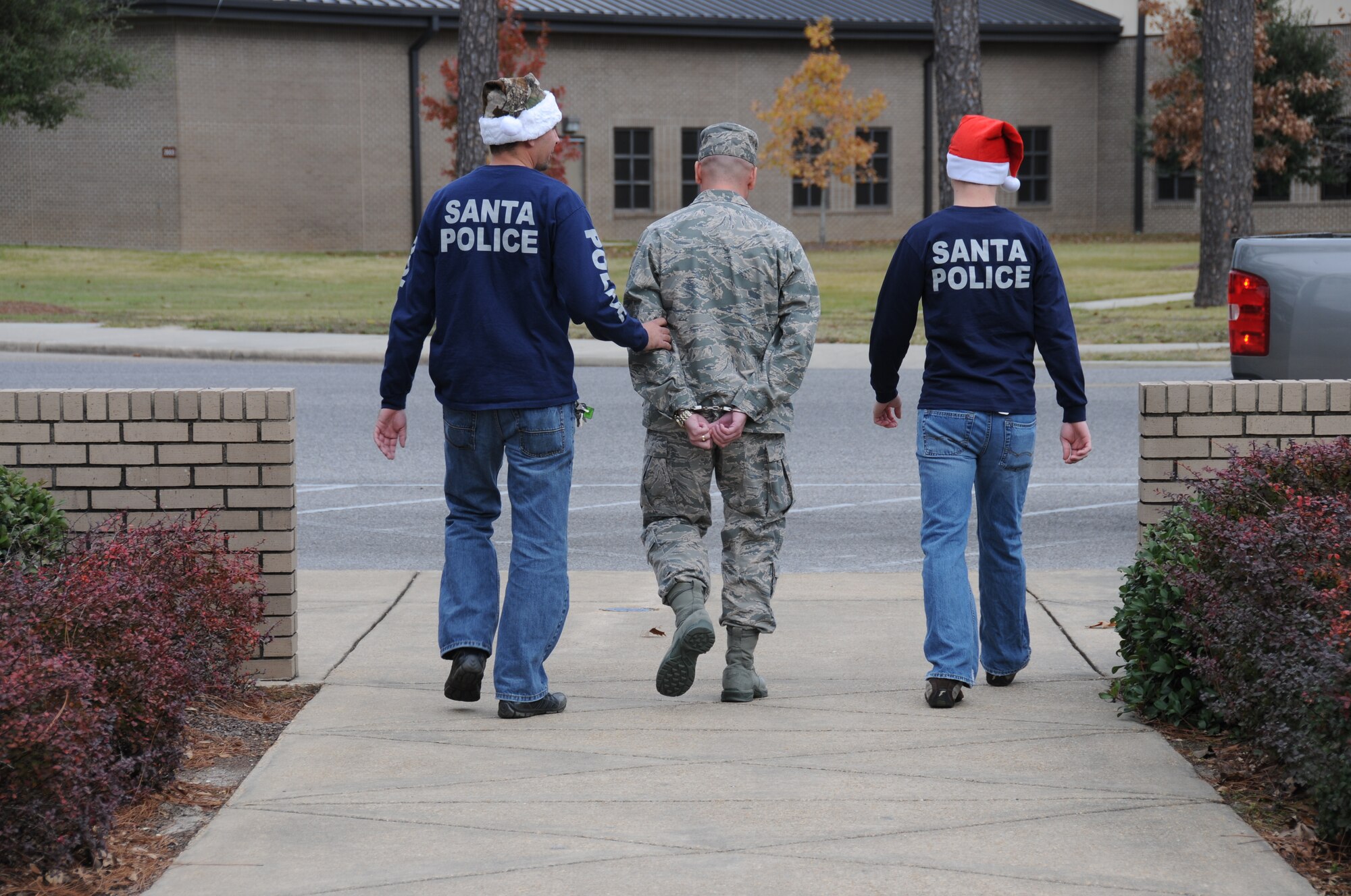 Lt. Col. Glen Downing, center, 81st TRW vice commander, was arrested while attempting to escape the Mathies NCO Academy Dec. 8. Staff Sgt. Chris Freimann, left, 332nd Training Squadron, and Airman 1st Class David Schlothauer, 81st SFS, apprehended Col. Downing without incident and drove him to a secure location. Bail matched the price paid for an inmate’s arrest and helped raise $4,000 to benefit Fisher House and finance the 81st SFS Christmas party.  (U.S. Air Force photo by Kemberly Groue)