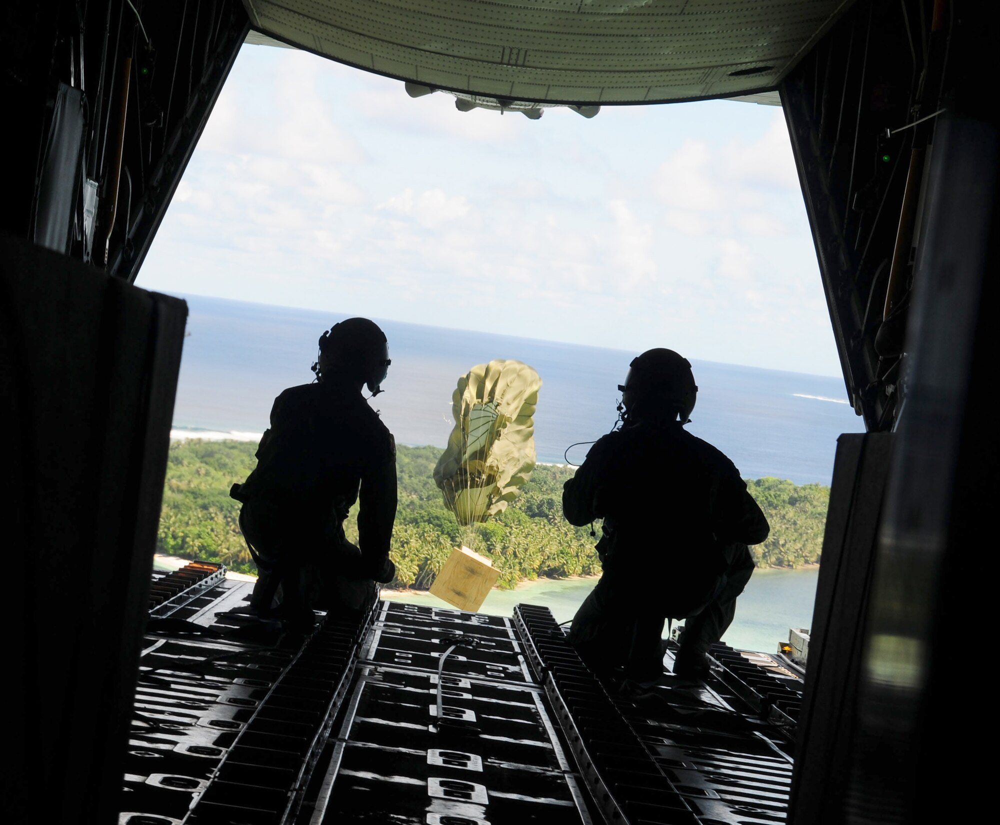 Airmen watch as the parachute deploys and a box of humanitarian goods drops during Operation Christmas Drop Dec. 14, 2010, over the Yap Islands, Commonwealth of the Northern Marianas Islands. The Airmen are assigned to the 36th Airlift Squadron at Yokota Air Base, Japan. (U.S. Air Force photo/Senior Airman Nichelle Anderson)