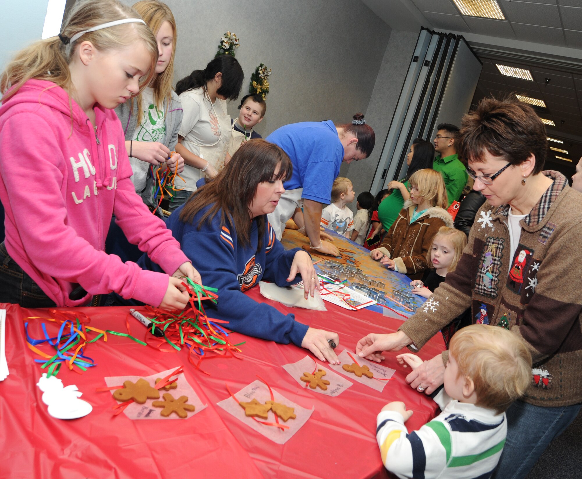 Jackie White, 22nd Force Support Squadron Library program coordinator, helps Team McConnell family members make gingerbread Christmas tree ornaments during Santa’s Visit Dec. 11, 2010, McConnell Air Force Base, Kan. Team McConnell members had the opportunity to spend time with family, take pictures with Santa, play free games, win prizes and participate in craft activities.  (U.S. Air Force photo/Senior Airman Maria A. Ruiz)  