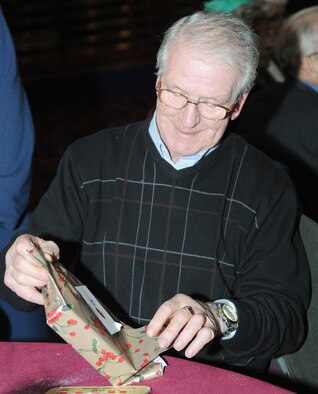 RAF MILDENHALL, England -- Bill Purdy opens a prize he won during bingo at the 29th Annual Senior Citizens Luncheon here Dec. 16, 2010. This event was organized by the Top Three and sponsored by several base organizations to help maintain partnerships with the local communities. (U.S. Air Force photo/Senior Airman Tabitha M. Lee) 