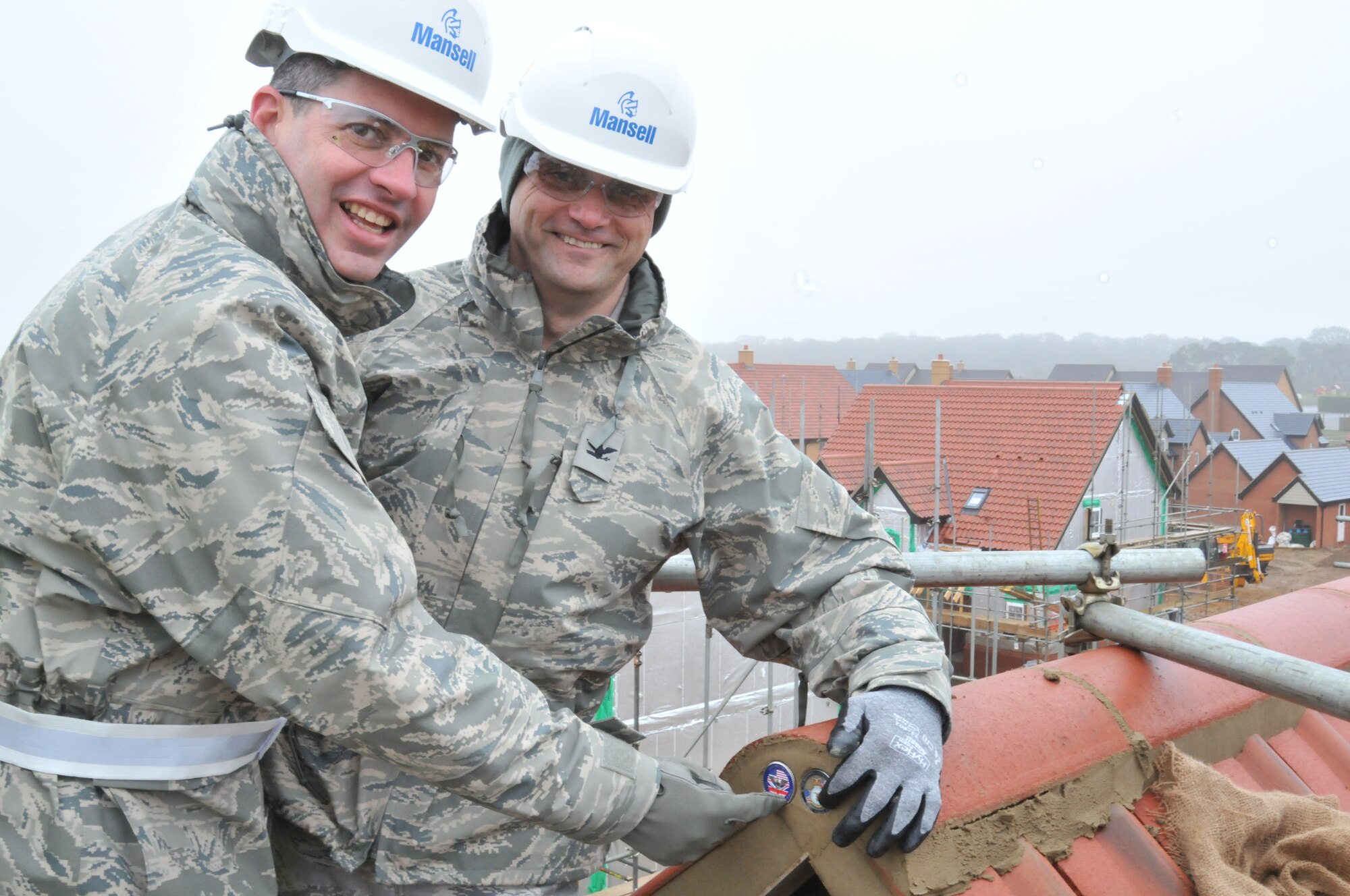 ROYAL AIR FORCE LAKENHEATH, England -- Col. William Lewis, 48th Fighter Wing vice commander (left), and Col. Michael Winters, 100th Air Refueling Wing vice commander, place unit coins in the final house in Liberty Village to have its roof completed Dec. 15. To date, 515 of 606 homes have been turned over to residents. (U.S. Air Force photo/Senior Airman David Dobrydney)