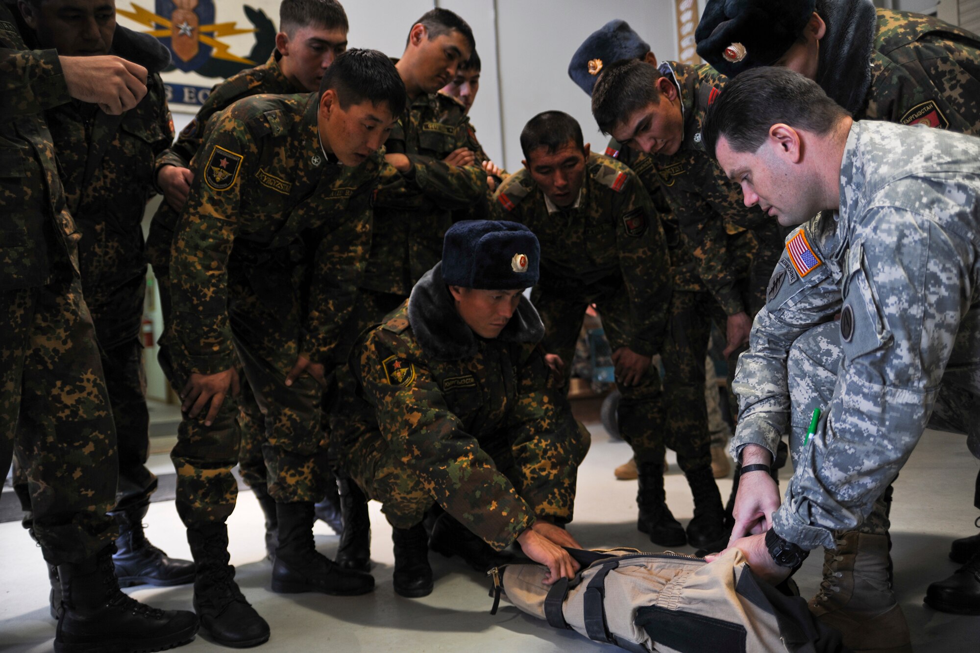 TRANSIT CENTER AT MANAS, Kyrgyzstan - Army Sgt. 1st Class Stephen Fitch, G-334th Explosive Ordnance Disposal non-commissioned officer, shows the quick escape zippers on how to take off a bomb suit during a U.S.-Kygyz military-to-military event held at the Transit Center at Manas Dec. 16. (U.S. Air Force photo/Staff Sgt. Nathan Bevier)