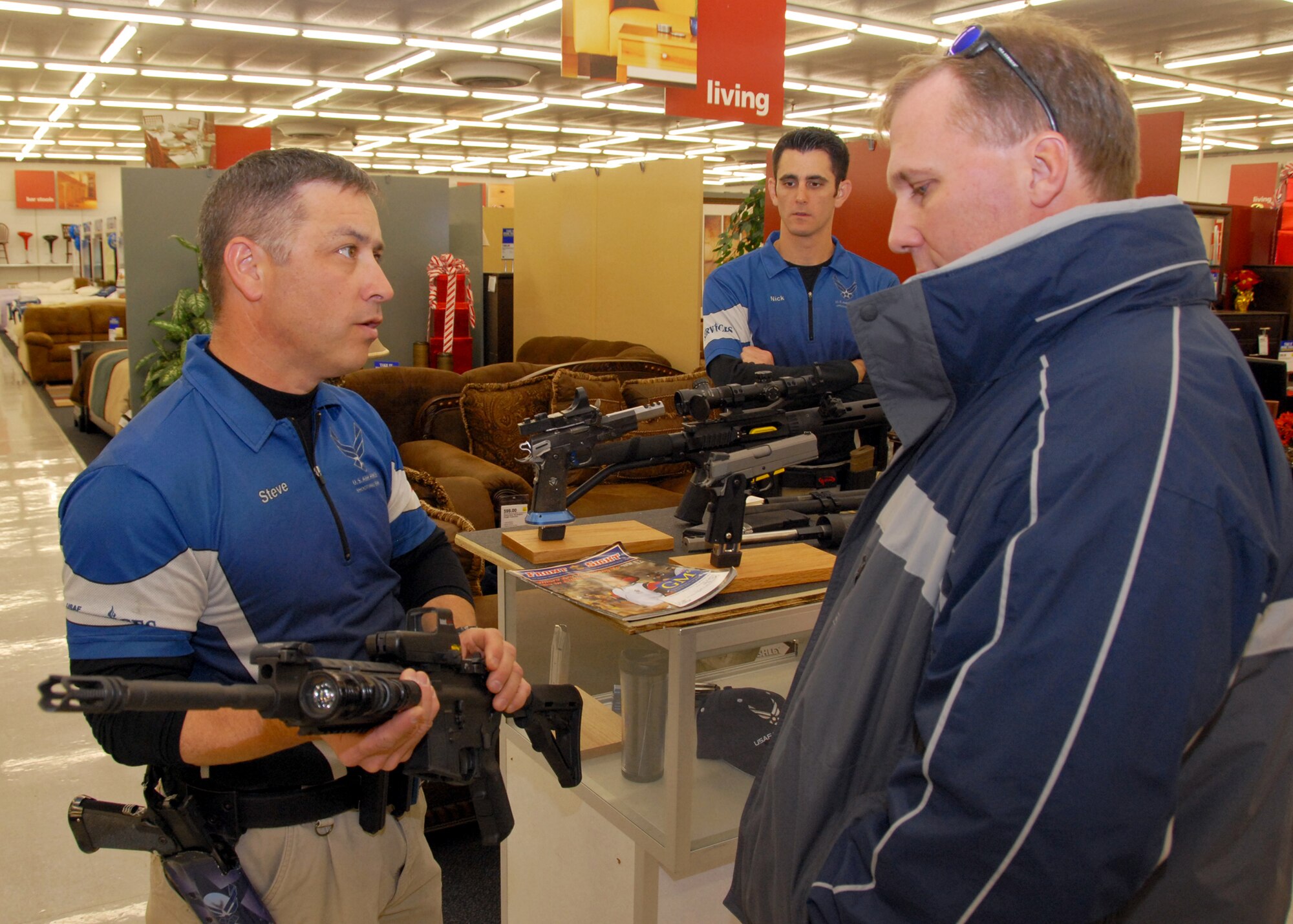 Maj. Steve Dennis, Air Force Action Shooting Team captain, shows a Colt Law Enforcement Military Use AR-15 rifle to Greg Hoffman, 28th Test and Evaluation Squadron, at the shooting display at the base exchange.  (U.S. Air Force photo/Kevin Gaddie)