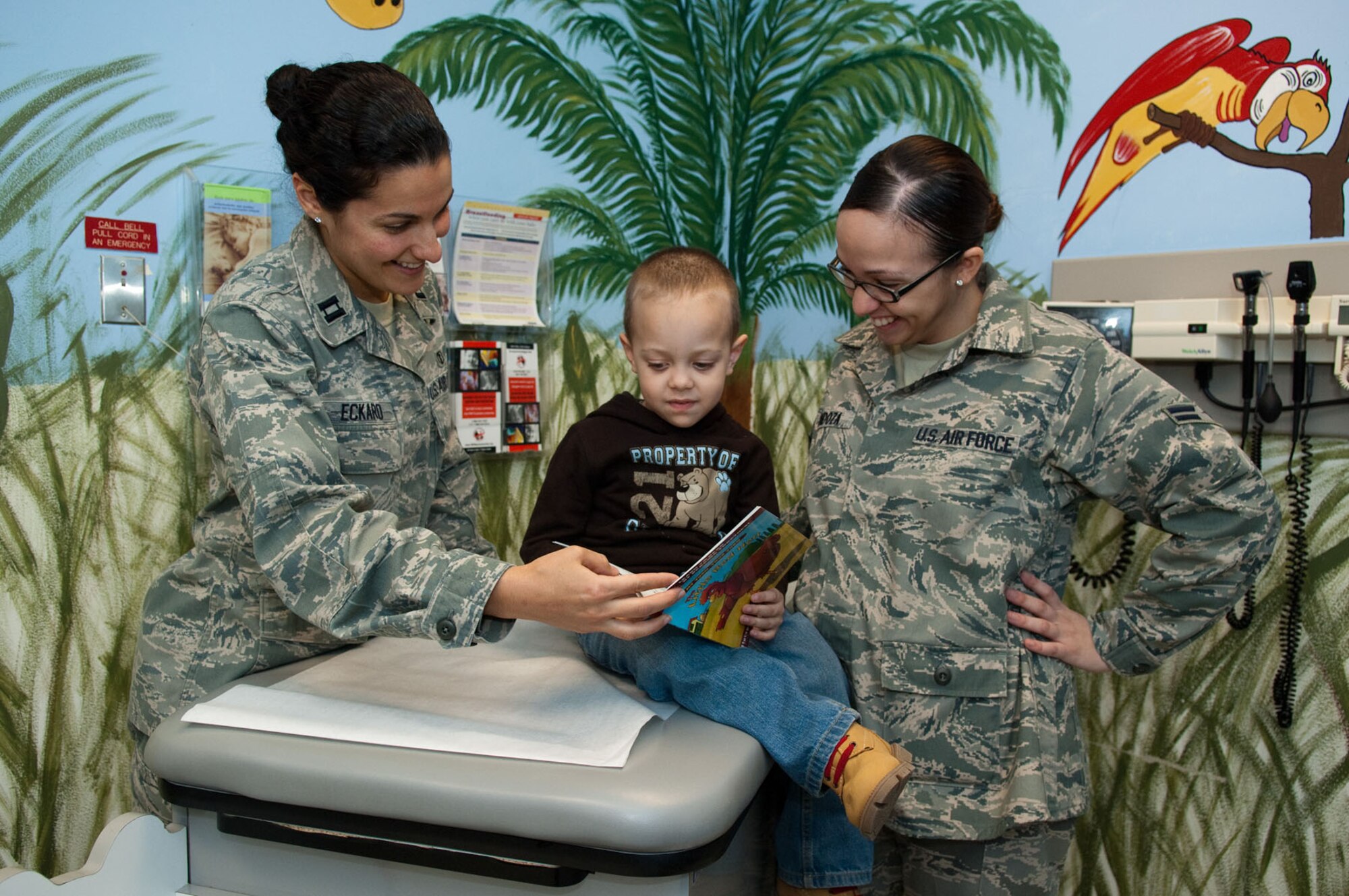 HANSCOM AIR FORCE BASE, Mass. – Capt. Laina Eckard (left) reads a book to Airman 1st Class Karina Mendoza’s son, Jakeb, during a Well Child visit at the base clinic on Dec. 14. Captain Eckard is the medical director of the Reach Out and Read program, an initiative designed to expose children to books at an early age and educate parents about the importance of reading with their children. (U.S. Air Force photo by Rick Berry)