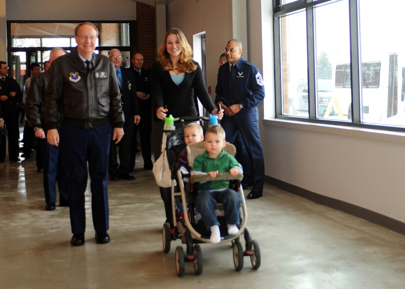 MINOT AIR FORCE BASE, N.D. – Mrs. Katie Becker, wife of deployed Staff Sgt. Dustin Becker, 5th Aircraft Maintenance Squadron weapons loader and Lt. Gen. Frank Klotz, Air Force Global Strike Command commander, walk with her twin boys for the first official transit through a new breezeway between Minot’s Base Exchange and Commissary following a ribbon-cutting ceremony here Dec. 13. The breezeway will protect Minot Airmen, families and retirees from harsh weather during the winter months as they walk from one building to the other. (U.S. Air Force photo/Airman 1st Class Aaron-Forrest Wainwright)