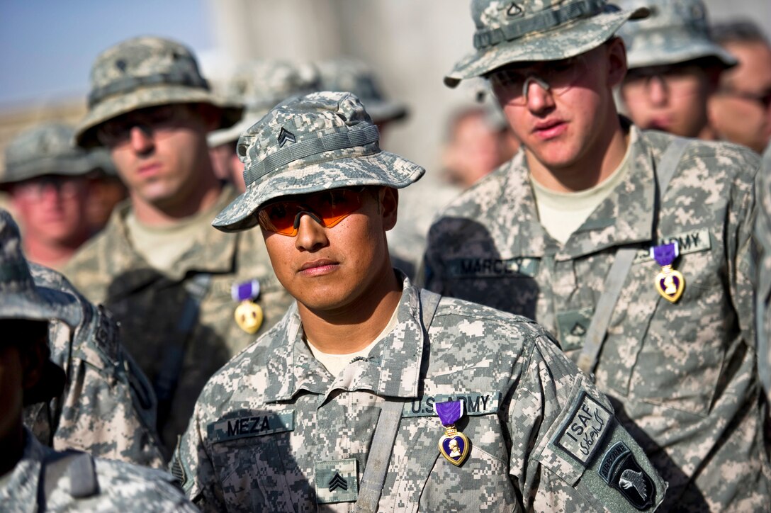 U.S. Army Spc. Charles Parno, left, Sgt. Gabriel Meza, center, and Pfc. Brian Marcey stand in formation after receiveing Purple Hearts from U.S. Navy Adm. Mike Mullen, chairman of the Joint Chiefs of Staff, during a ceremony on Forward Operating Base Wilson in Kandahar, Afghanistan, Dec.16, 2010.