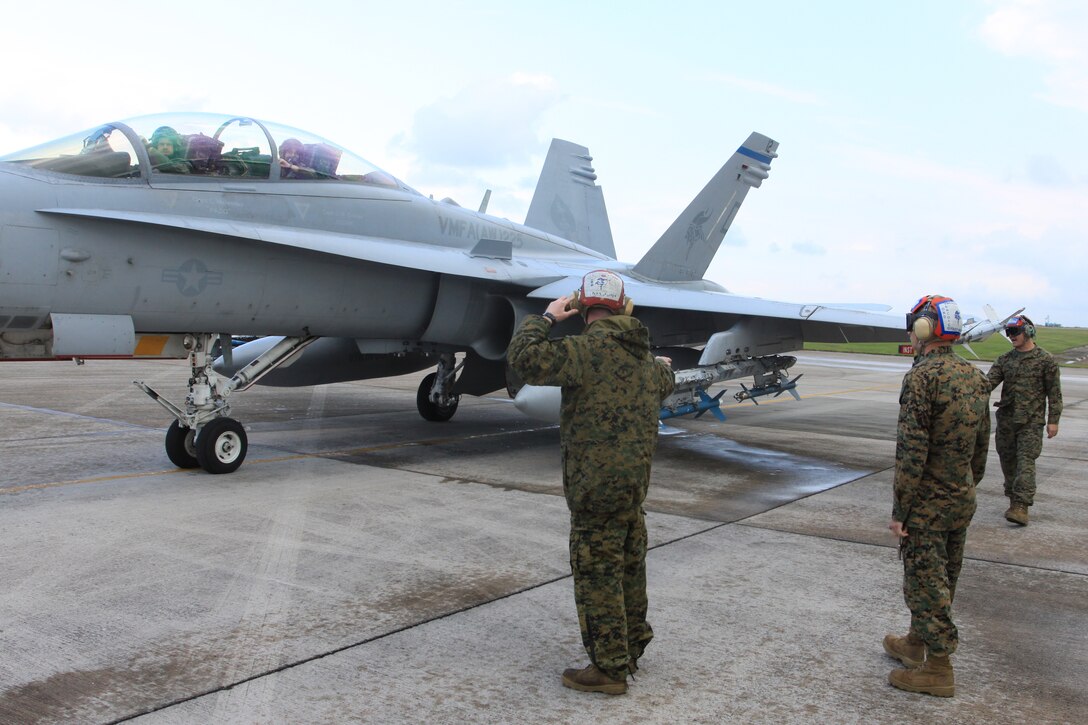 Lance Cpl. Kent Hinderleider, Marine All-Weather Fighter Attack Squadron 225 aviation ordnance technician, uses hand and arm signals to direct his team of technicians through an ordnance safety check. The runway check is the last of a series of ordnance checks before pilots are cleared for takeoff.