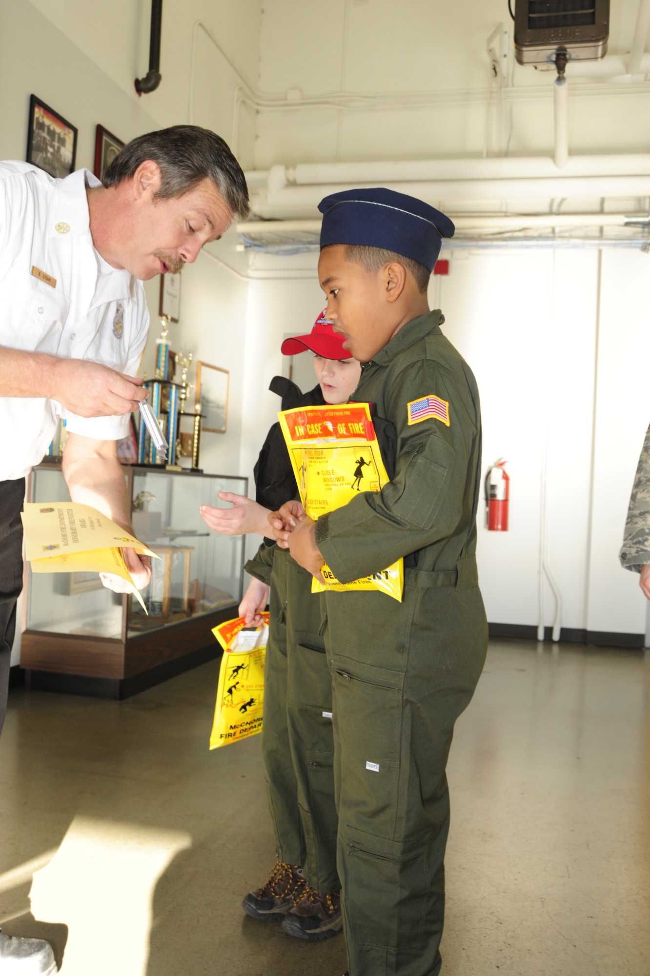 Bret Stohr, left, 627th Civil Engineer Squadron assistant fire chief, presents Mark Moore Jr. with a fire coin during a tour of the fire station Dec. 17 at McChord Field, Joint Base Lewis-McChord, Wash. (U.S. Air Force photo/Airman Leah Young)