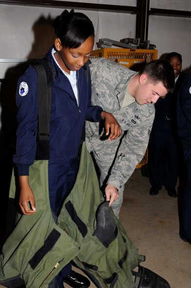 Senior Airman Bryan Bell, 2nd Civil Engineer Squadron Explosive Ordnance Disposal Flight technician, helps Precious Smith, a 14-year-old Marshall High School Junior and Reserve Officer Training Course student , into a bomb suit during a tour of the facility on Barksdale Air Force Base, La., Dec. 13. (U.S. Air Force photo/Staff Sgt. Terri Barriere)