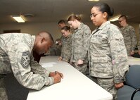 Chief Master Sgt. Juan Lewis, 502nd Air Base Wing command chief, signs Airman Isamar Liz's goal card at the First Term Airmen Center Dec. 15. Each Airman at FTAC completes a goal card which lists five goals they pledge to achieve during their first enlistment. (U.S. Air Force photo/Robbin Cresswell)