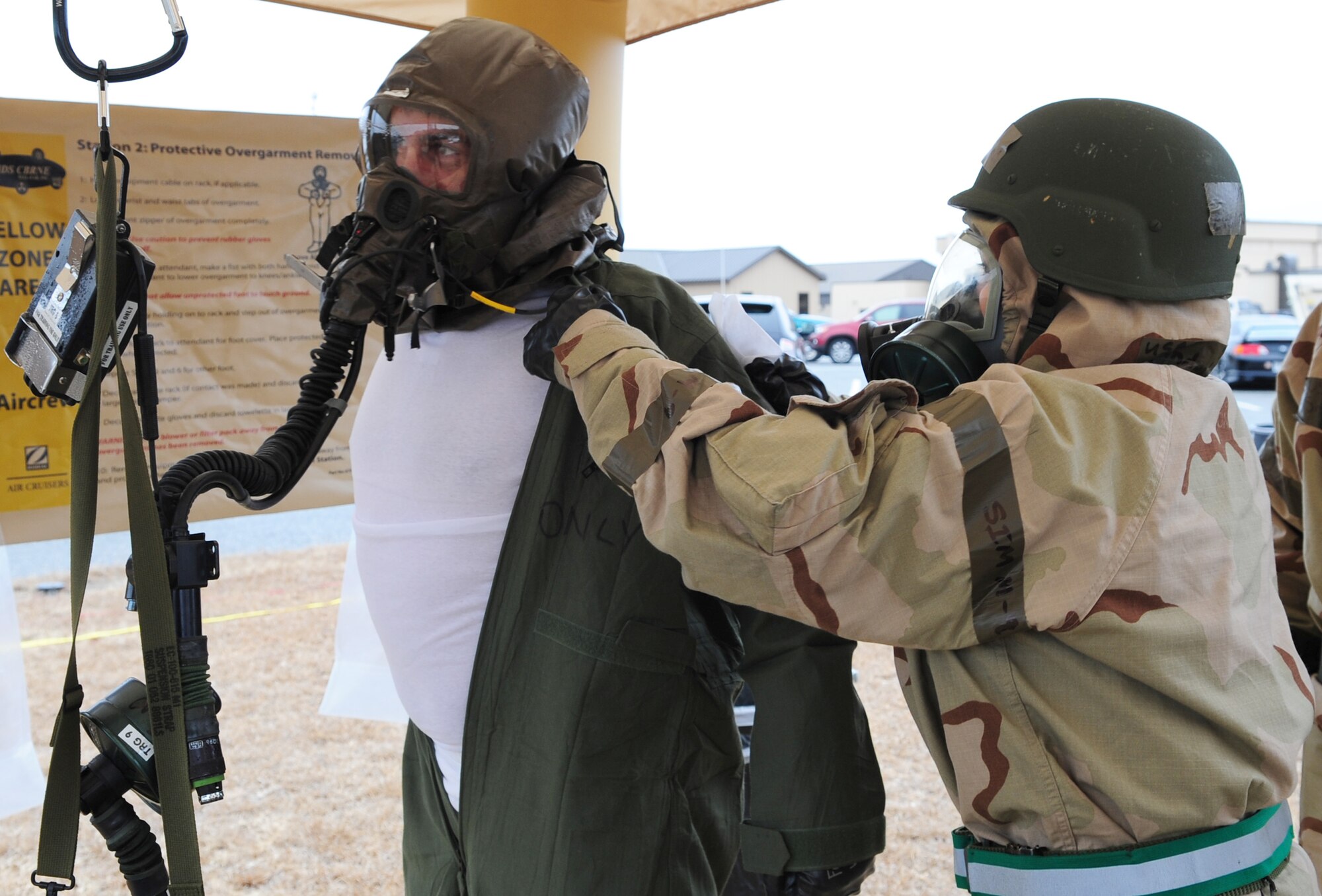 MOODY AIR FORCE BASE, Ga. -- Tech. Sgt. Evelinda Lombard, 23rd Operations Support Squadron aircrew flight equipment journeyman, helps remove the overgarment of a 23rd Fighter Group A-10C Thunderbolt II pilot, Dec. 17. The decontamination procedure is divided into three zones: cleansing, removal of equipment and the shower. (U.S. Air Force photo/Senior Airman Stephanie Mancha)(RELEASED)