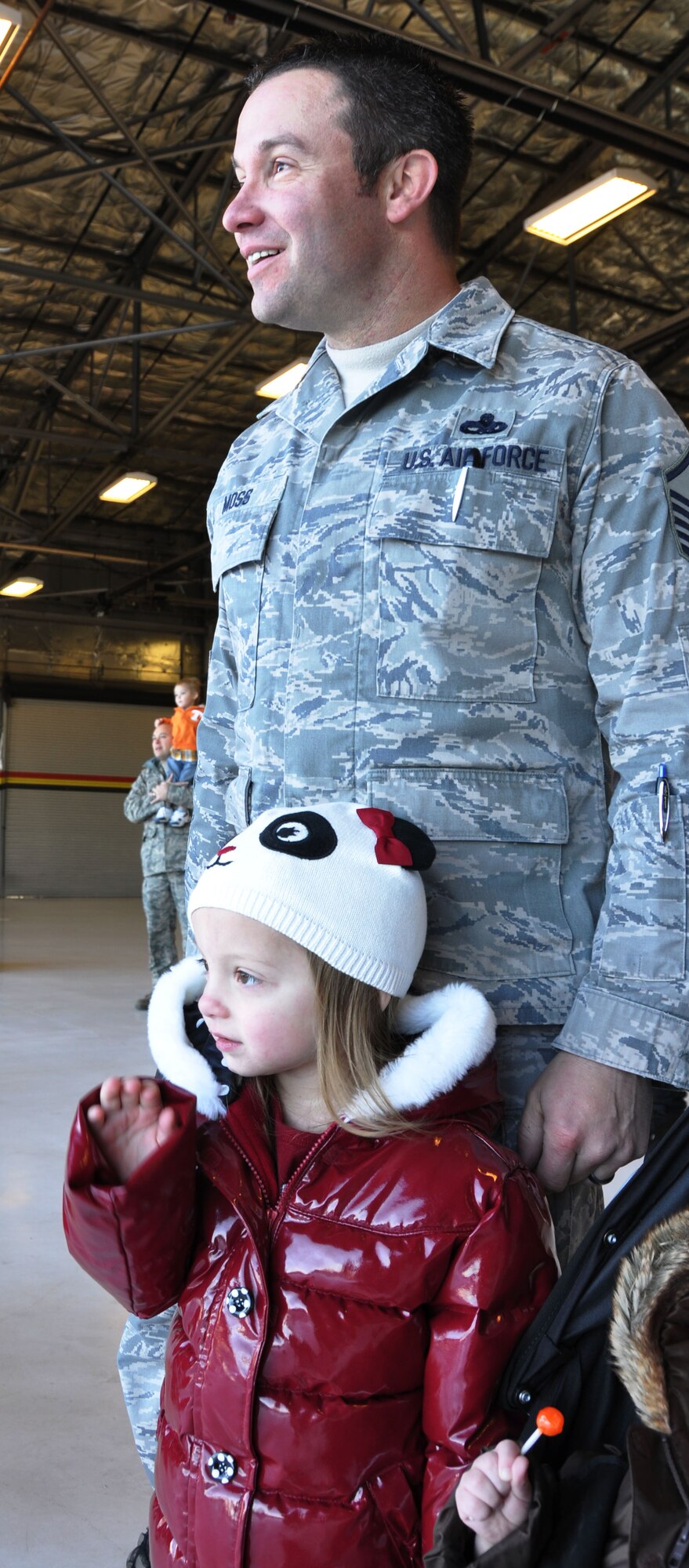 Master Sgt. Jason Moss of the 419th Aircraft Maintenance Squadron, and his 3-year-old daughter, Aniston, look on as Santa arrives at the wing Christmas party Dec. 16. (U.S. Air Force photo/Kari Tilton)