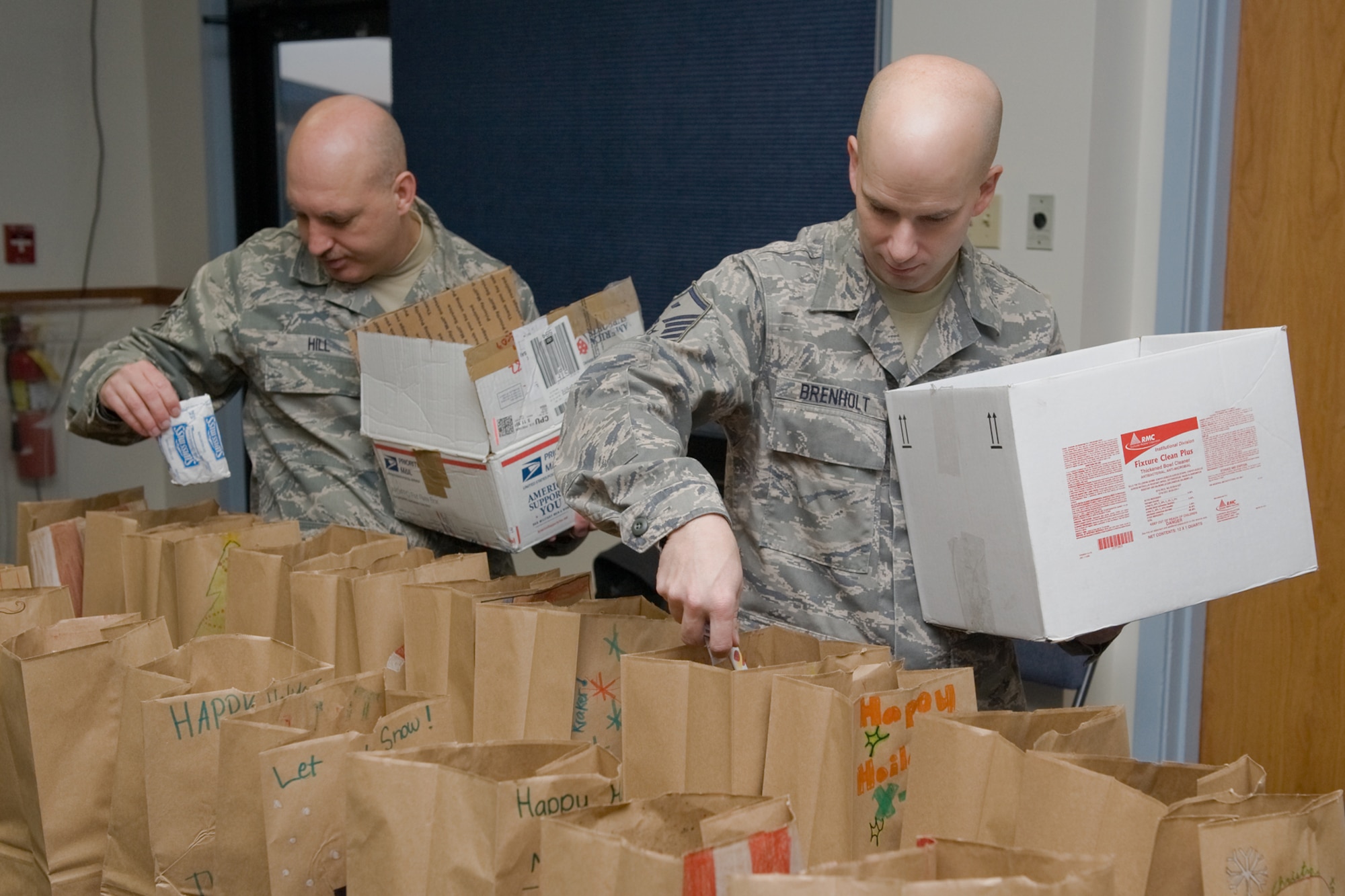 Master Sgt. Jason Hill, 341st Logistics Readiness Squadron first sergeant and Master Sgt. Matthew Brenholt, 341st Medical Group first sergeant, fill holiday bags destined for the dormitories with donated treats Dec. 15 at the chapel annex. Delivering gooodie bags to the single Airmen on base has become an annual holiday tradition for the first sergeants. (U.S. Air Force photo/Beau Wade)