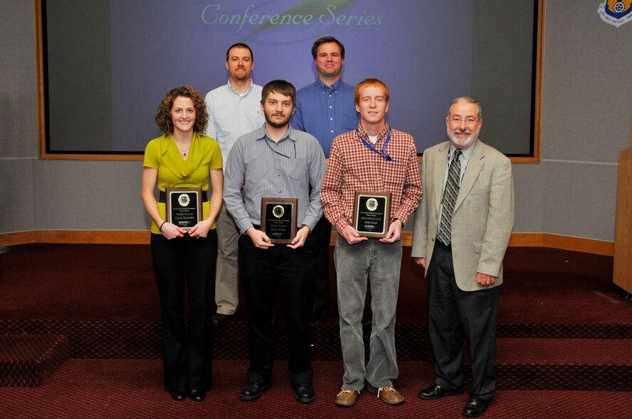 Technical Poster Contest winners accepted their plaques Nov 18. (front row) Carrie Reinholtz, third place (tie); Brian Binkley, third place (tie); Andy Escue, second place; Tom Best, AEDC technical director of plans and programs. (back row) Dustin Crider, Aerospace Testing Alliance (ATA) Space and Missiles Technology project manager and chair of the American Institute of Aeronautics and Astronautics (AIAA) Tennessee Section Young Professionals; Dr. Joseph Sheeley, ATA technology engineer in Facilities and Test Technology and past chairman of AIAA. (Photo by Rick Goodfriend)