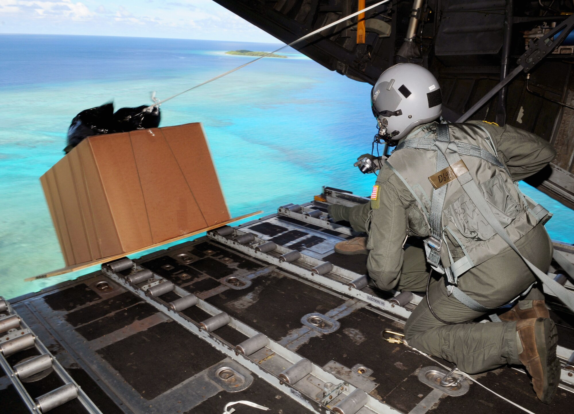 Senior Airman Joseph Doria and Capt. Stanley Kimball watch after pushing a box of humanitarian assistance goods out of a U.S. Air Force C-130 Hercules, call sign "Santa 23" to its drop-zone in Yap Islands during Operation Christmas Drop, Dec. 14, 2010. This year more than 60 boxes will be dropped to 55 Island weighing in at more than 20,000 pounds.Airman Doria is a 36th Airlift Squadron loadmaster from Yokota Air Base, Japan. Captain Kimball is the 36th Airlift Squadron flight surgeon. (U.S. Air Force photo/Senior Airman Nichelle Anderson)

