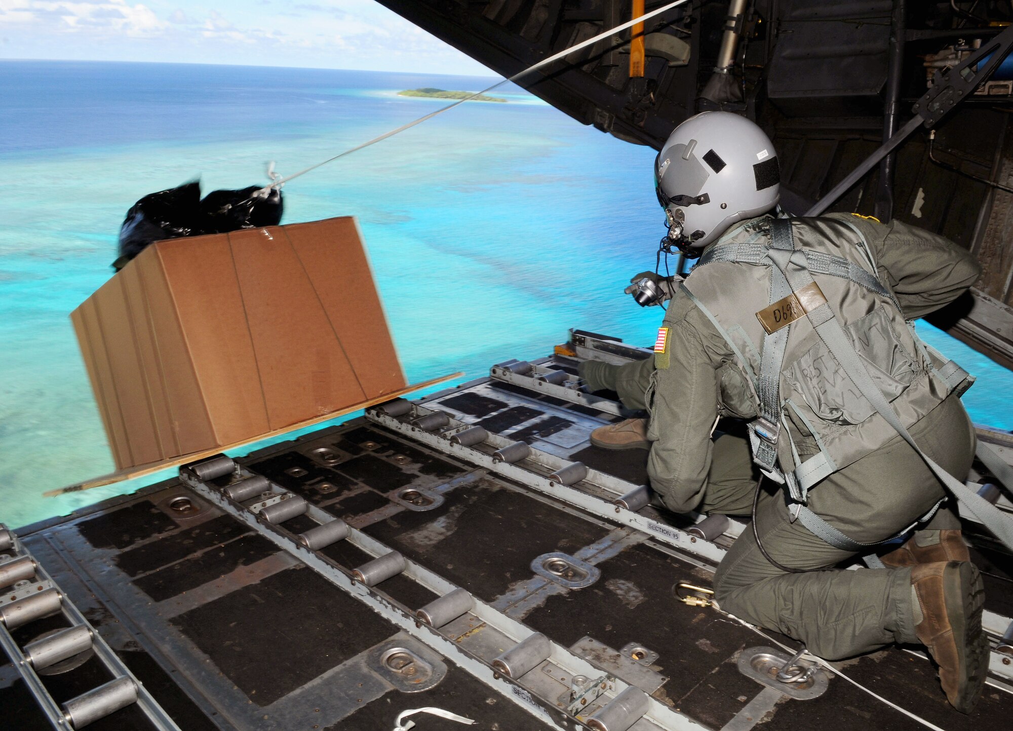 Senior Airman Joseph Doria and Capt. Stanley Kimball watch after pushing a box of humanitarian assistance goods out of a U.S. Air Force C-130 Hercules, call sign "Santa 23" to its drop-zone in Yap Islands during Operation Christmas Drop, Dec. 14, 2010. This year more than 60 boxes will be dropped to 55 Island weighing in at more than 20,000 pounds.Airman Doria is a 36th Airlift Squadron loadmaster from Yokota Air Base, Japan. Captain Kimball is the 36th Airlift Squadron flight surgeon. (U.S. Air Force photo/Senior Airman Nichelle Anderson)
