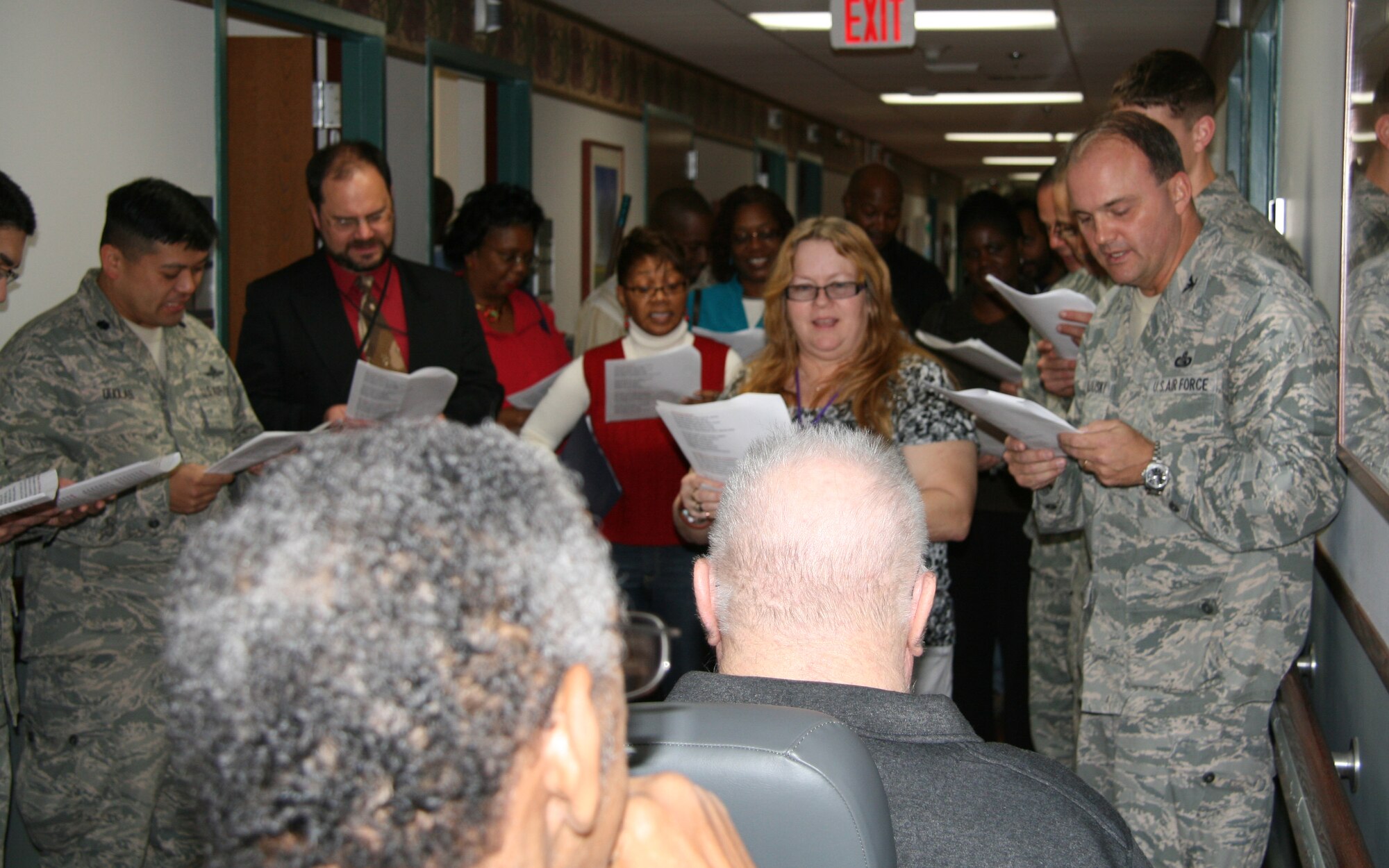 Air Combat Command Airmen from Langley Air Force Base, Va., line the hallways of the Hampton Veterans Medical Center while singing, "Joy to the World" during a visit to the hospital, Dec. 10. Along with caroling through the halls, holiday edibles were brought to several wings and a formal presentation was held honoring the retired servicemembers with a Vietnam era footlocker memento. (U.S. Air Force photo/Justin R. Oakes)