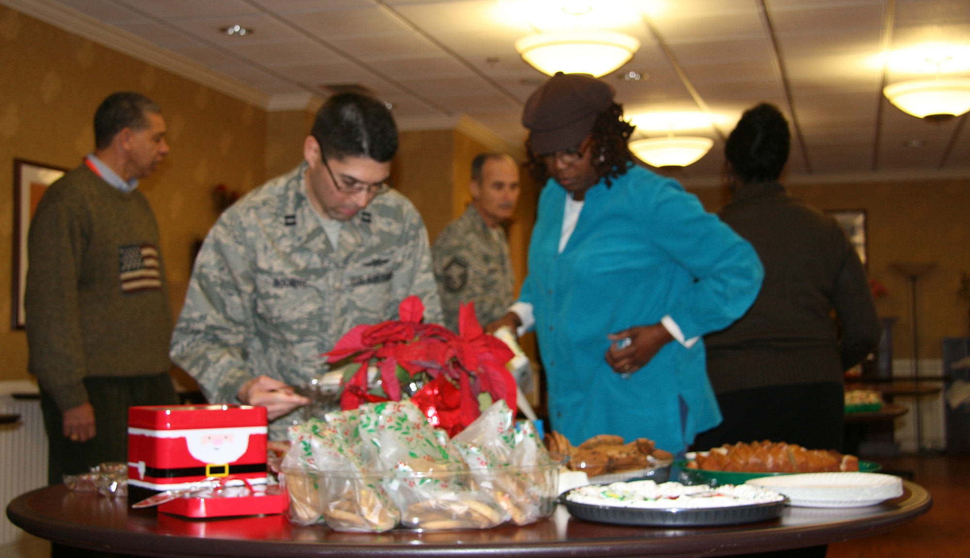 Airmen and Department of Defense civilians from Langley Air Force Base, Va., prepare tables full of holiday edibles for veterans during a trip to the Hampton Veterans Medical Center, Dec. 10. Airmen spread holiday cheer by singing Christmas carols down the halls of the hospital, bringing food and presented the retired servicemembers with a memento. (U.S. Air Force photo/Justin R. Oakes) 