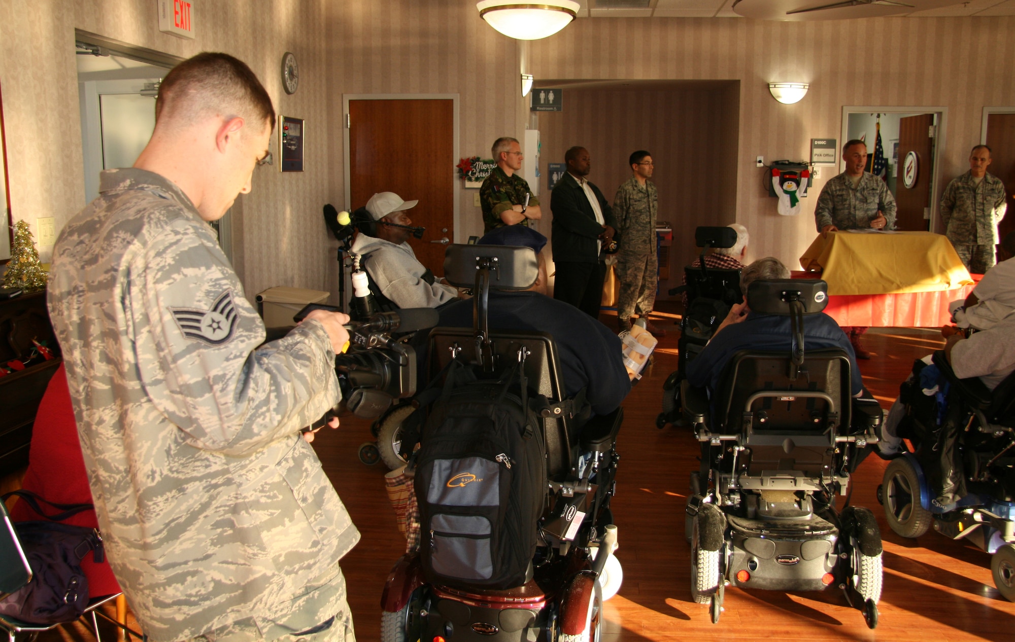 Staff Sgt. Jeff Howerton, Air Combat Command Public Affairs broadcaster, records the unveiling of an all-service memento given to retired servicemembers at the Hampton Veterans Medical Center, Dec. 10. Airmen from Langley Air Force Base, Va., met with veterans from various wars and branches and presented the gift as a thank you for their support and sacrifice. (U.S. Air Force photo/Justin R. Oakes)