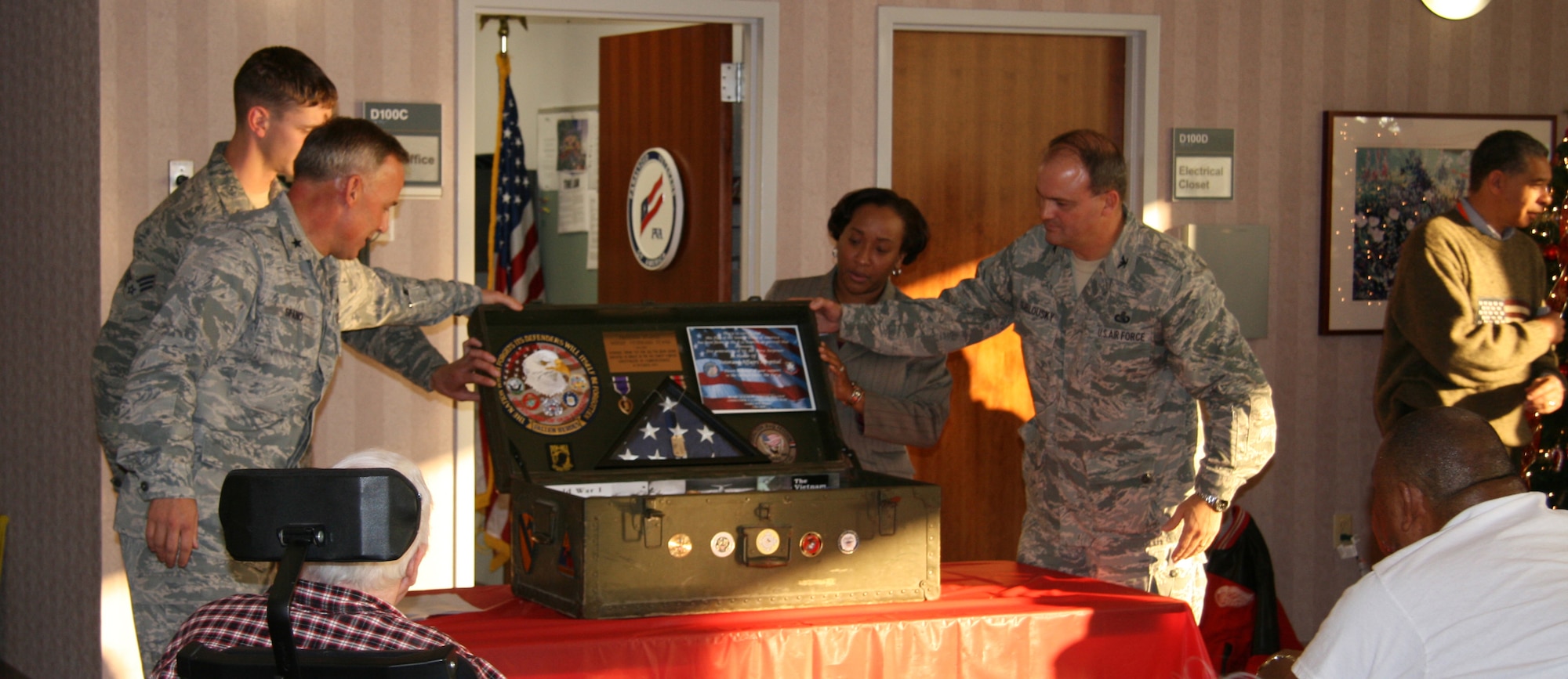 Brig. Gen. Steven Spano, Air Combat Command Communications director, Senior Airman Jonathan Harding, 633d Logistics Readiness Squadron vehicle operator, Col. Joe Sublousky, ACC Warfigher Technology Division chief, along with a hospital administrator present a Vietnam era footlocker memento to the veterans at the Hampton Veterans Medical Center, Dec. 10. Airmen from Langley Air Force Base, Va., visited the medical center to sing carols, bring food and honor the veterans with a holiday gift. (U.S. Air Force photo/Justin R. Oakes)