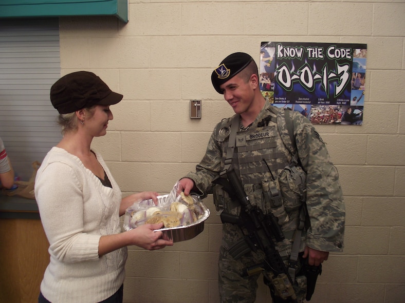 Amy Beers, wife of Lt. Col. Jason Beers, 377th Security Forces Squadron commander, gives Senior Airman Andrew Brodeur, 377th Security Forces Squadron, a bag of cookies from the security forces spouses.