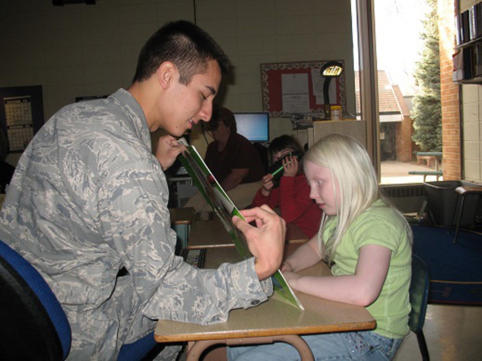A cadet volunteer reads to a child at the Colorado School for the Deaf and Blind in Colorado Springs Dec. 8, 2010. Seven cadets, including four enrolled in a Behavioral Science 310 class, created audiobooks for the CSDB students. (courtesy photo/Diane Covington)