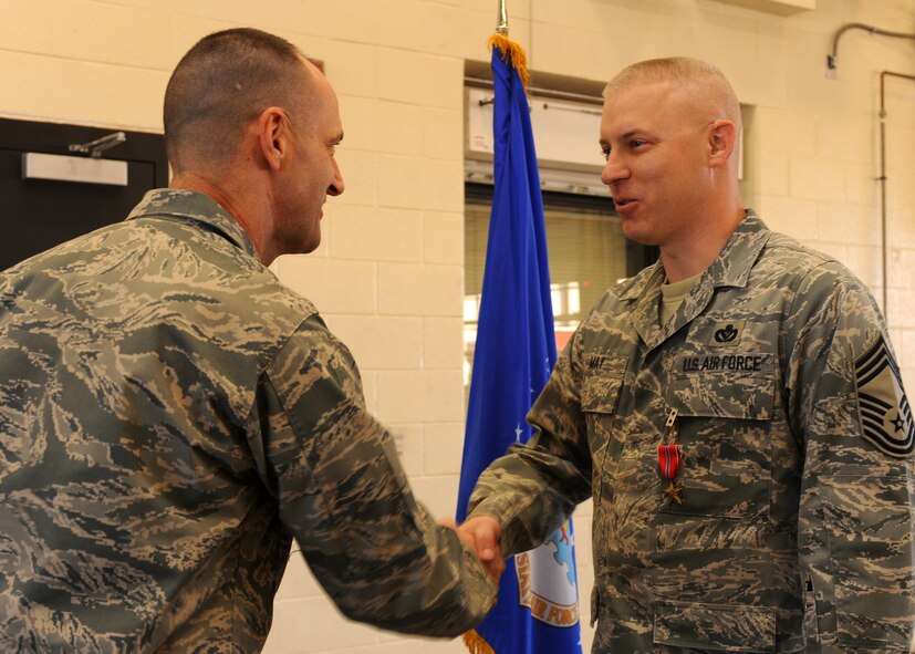 DYESS AIR FORCE BASE, Texas -- Col. David Been, 7th Bomb Wing commander, presents Chief Master Sgt. Christopher May, 7th Civil Engineer Squadron, with the Bronze Star Medal Dec. 16, during a ceremony at the fire department here. Chief May served as the 732nd Expeditionary Prime Beef Squadron superintendent at Balad Air Base, Iraq. While deployed he executed 200 logistic patrol movements, 90,000 convoy man-miles and $117 million in engineering projects supporting operating locations across Iraq. He also directed the completion of 48 horizontal and vertical troop labor projects valued at over $9 million and oversaw $50 million in joint forces essential projects at 24 locations, as well as the design and construction of over 60 schools, bridges and road projects for 7 million Iraqi citizens. (U.S. Air Force photo/Jenifer H. Calhoun)  