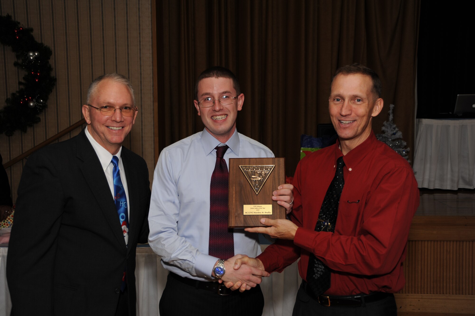 U.S. Navy Petty Officer 1st Class Matthew M. Bradley, Naval Air Facility Misawa mass communication specialist, receives his NAFM Junior Sailor of the Year award plaque from U.S. Navy Command Master Chief Michael Napier, NAFM CMC, left, and U.S. Navy Capt. James D. Haugen, NAFM Commanding Officer at Misawa Air Base, Japan, Dec. 2, 2010. The NAFM Junior Sailor of the Year is selected based upon E-5’s display of leadership, professionalism, dedication and superior performance.