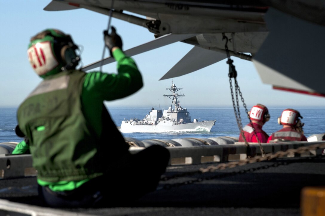 U.S. sailors work on the flight deck of the aircraft carrier USS Carl Vinson as the Arleigh Burke-class guided-missile destroyer USS Gridley transits nearby off the southern California coast, Dec. 12, 2010. 