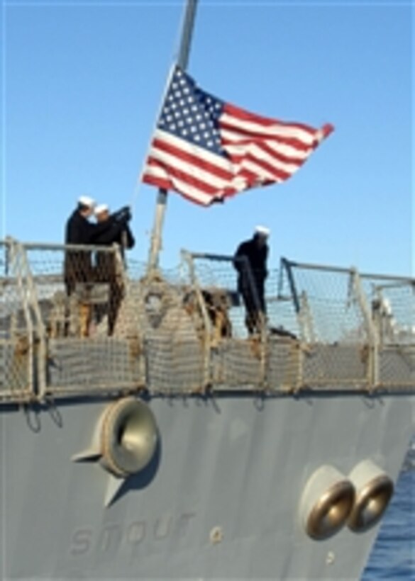 Sailors aboard the guided-missile destroyer USS Stout (DDG 55) remove the national ensign as the ship pulls away from the pier at Naval Station Norfolk on Dec. 15, 2010.  The Stout is deploying to the Mediterranean Sea and the U.S. 6th Fleet area of responsibility where it will be conducting its second Ballistic Missile Defense system deployment.  