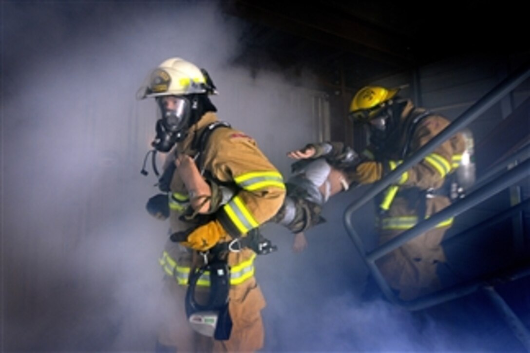 Commander of the 50th Space Wing Col. Wayne Monteith and firefighter Cody Marion join together to rescue a simulated victim from a smoke-filled room in the fire suppression training facility at Schriever Air Force Base, Colo., on Dec. 3, 2010.  The commander participated in the training to get firsthand experience.  