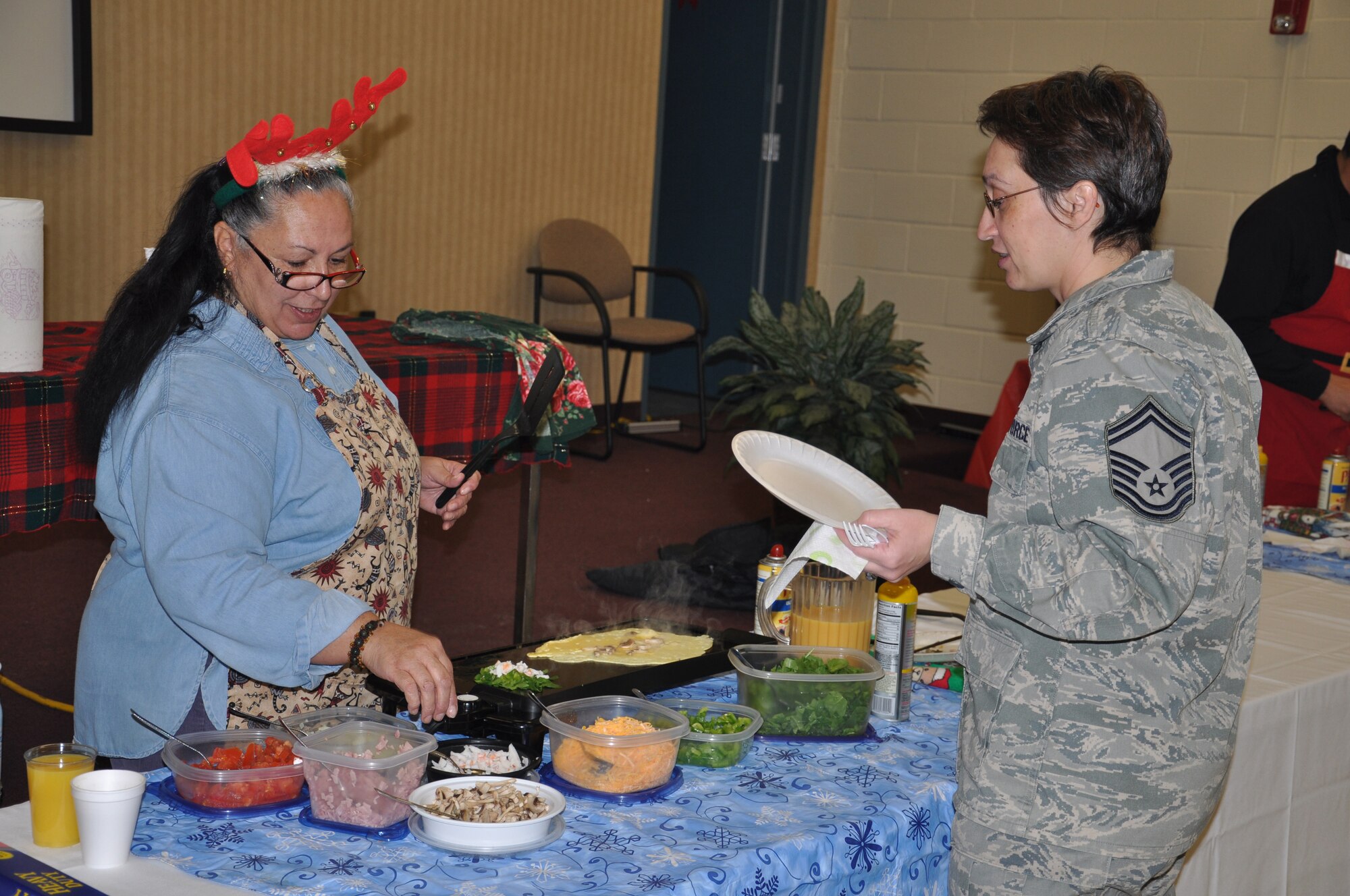 JOINT BASE MCGUIRE-DIX-LAKEHURST, N.J. -- Lydia Herrera of the 514th Air Mobility Wing prepares an omelet for a waiting customer Dec. 16. as fellow wing members, community guests and Joint Base McGuire-Dix Lakehurst co-workers attend the 22nd annual holiday breakfast held here. Participants enjoyed made-to-order omelets and a variety of other items. (U.S. Air Force photo/Master Sgt. Travon W. Dennis)