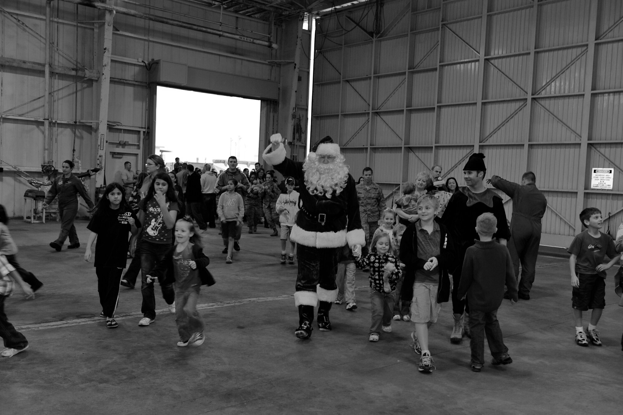 Santa Claus and one of his elves enters the 33rd Rescue Squadron hanger surrounded by 33rd and 31st Rescue Squadron personnel's chidlren at Kadena Air Base, Dec. 17. This is the fourth year the squadrons have had a kid's Christmas party featuring Santa, and it's become an important holiday tradition for the squadrons and something the kids look forward to all year. (U.S. Air Force photo/Staff Sgt. Lakisha A. Croley)      